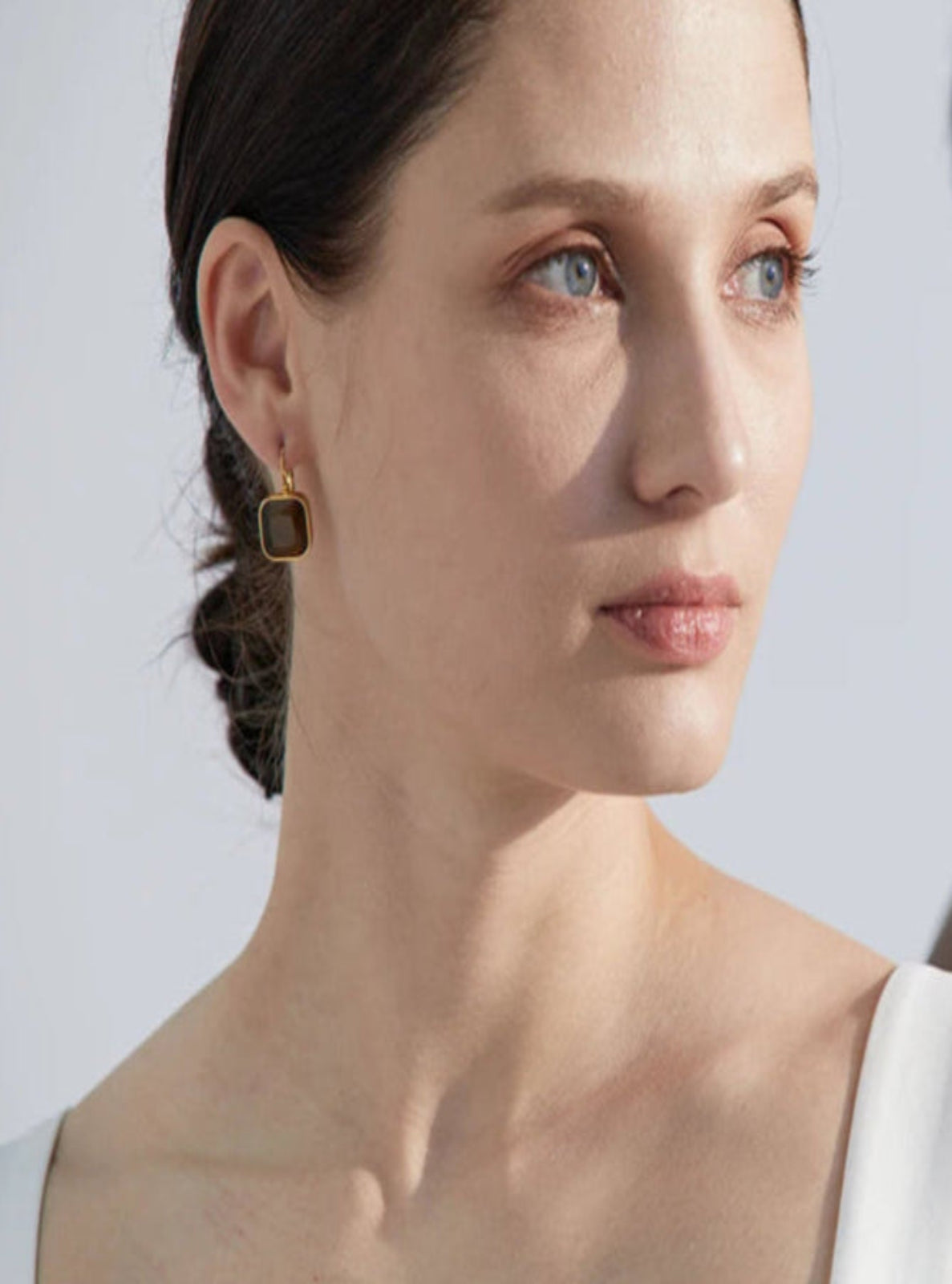 Two women wearing earrings with a plain background