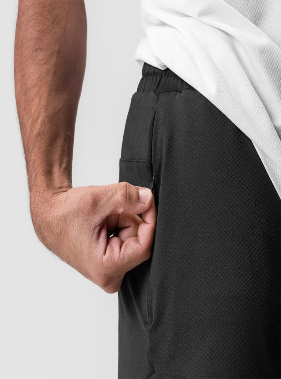 Person wearing black shorts with a white shirt, focusing on the waistband.