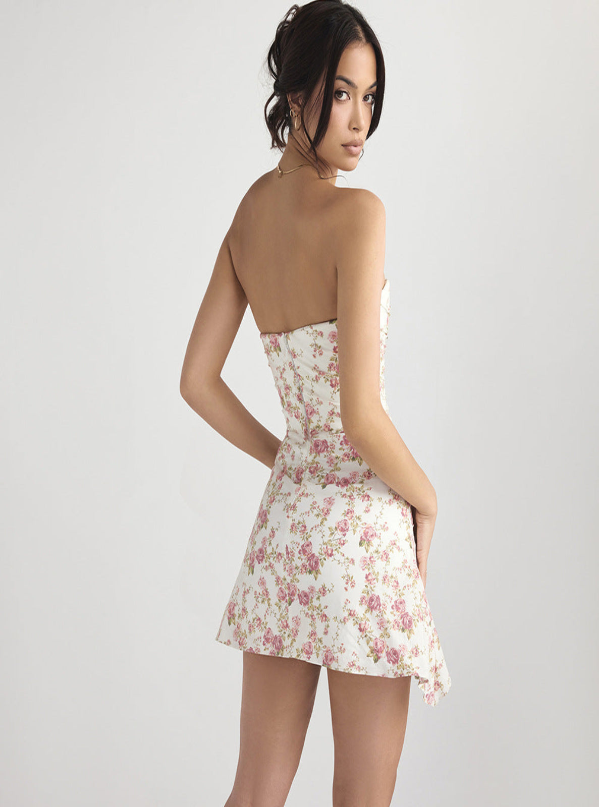 Woman wearing a strapless floral dress on a plain background