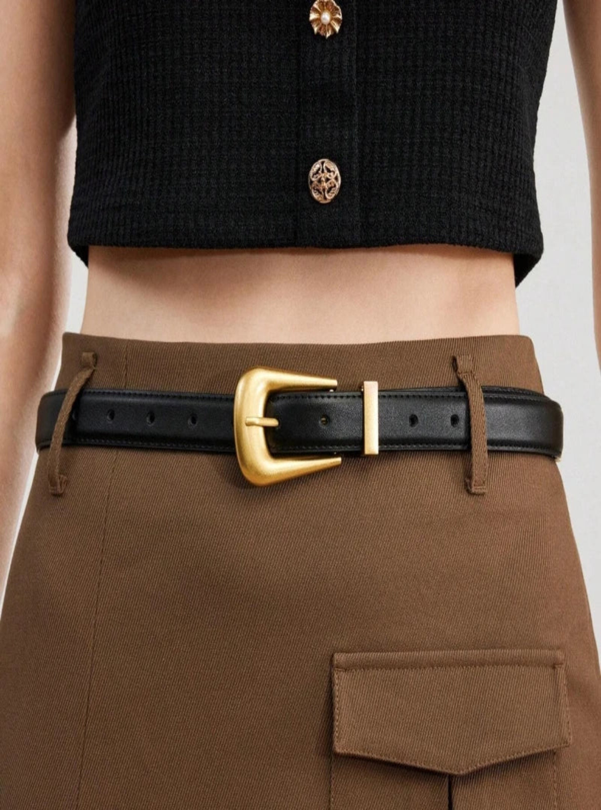 Brown pants with a black belt and gold buckle worn by a person.