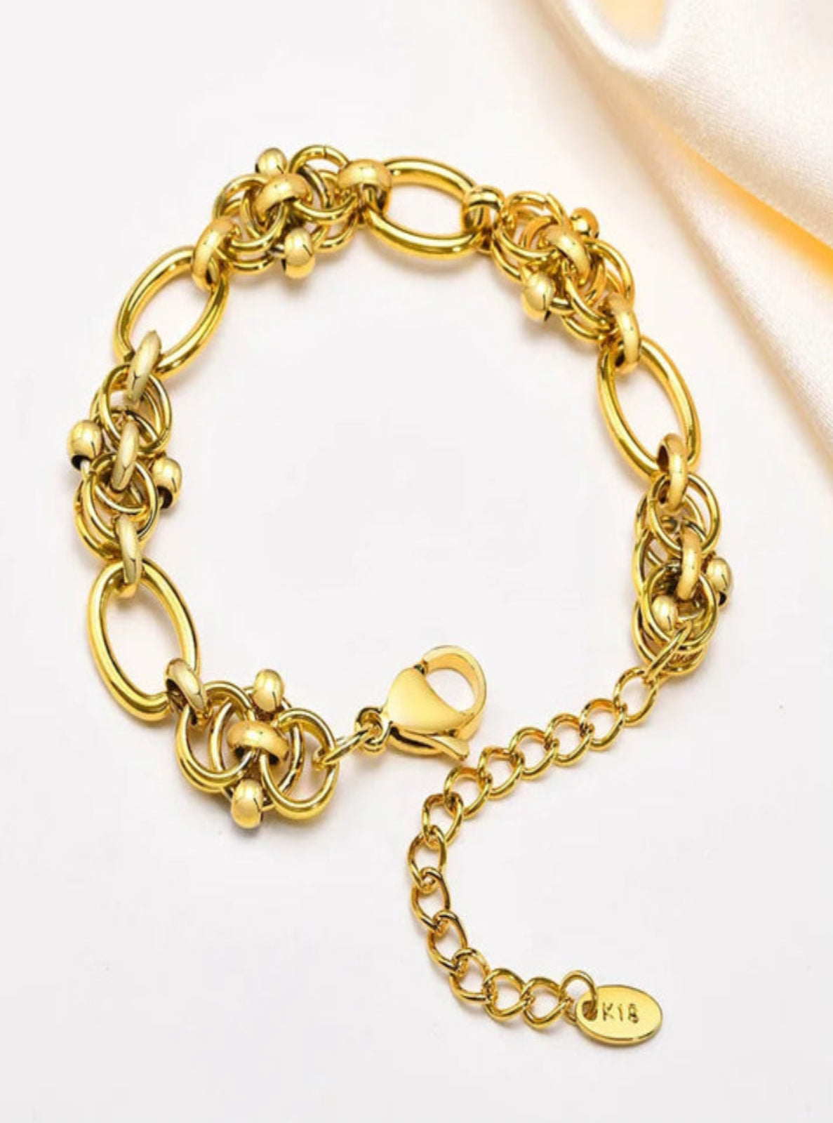 Gold chain bracelet with a clasp on a light background
