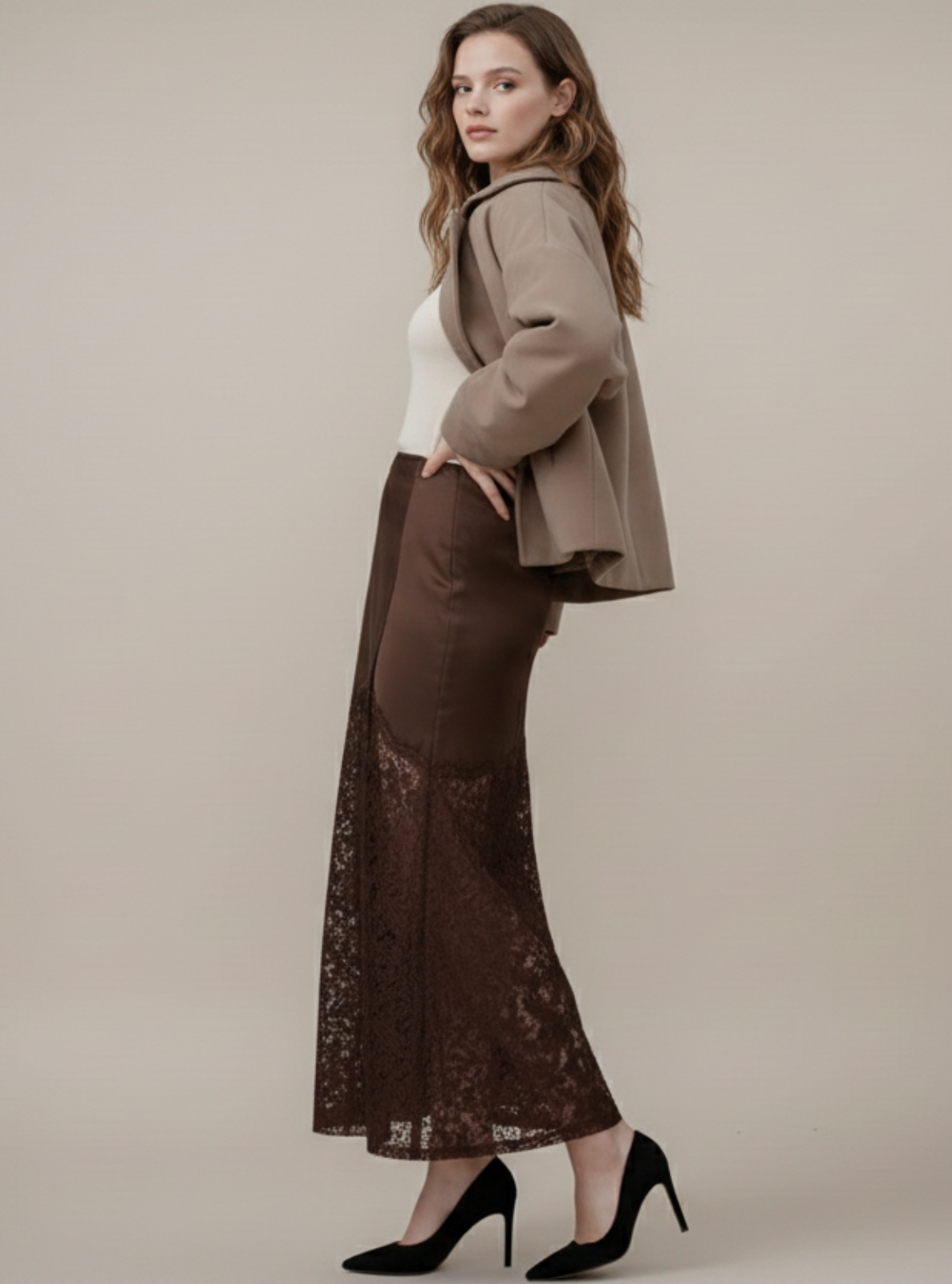 Woman wearing a brown jacket and lace skirt on a beige background