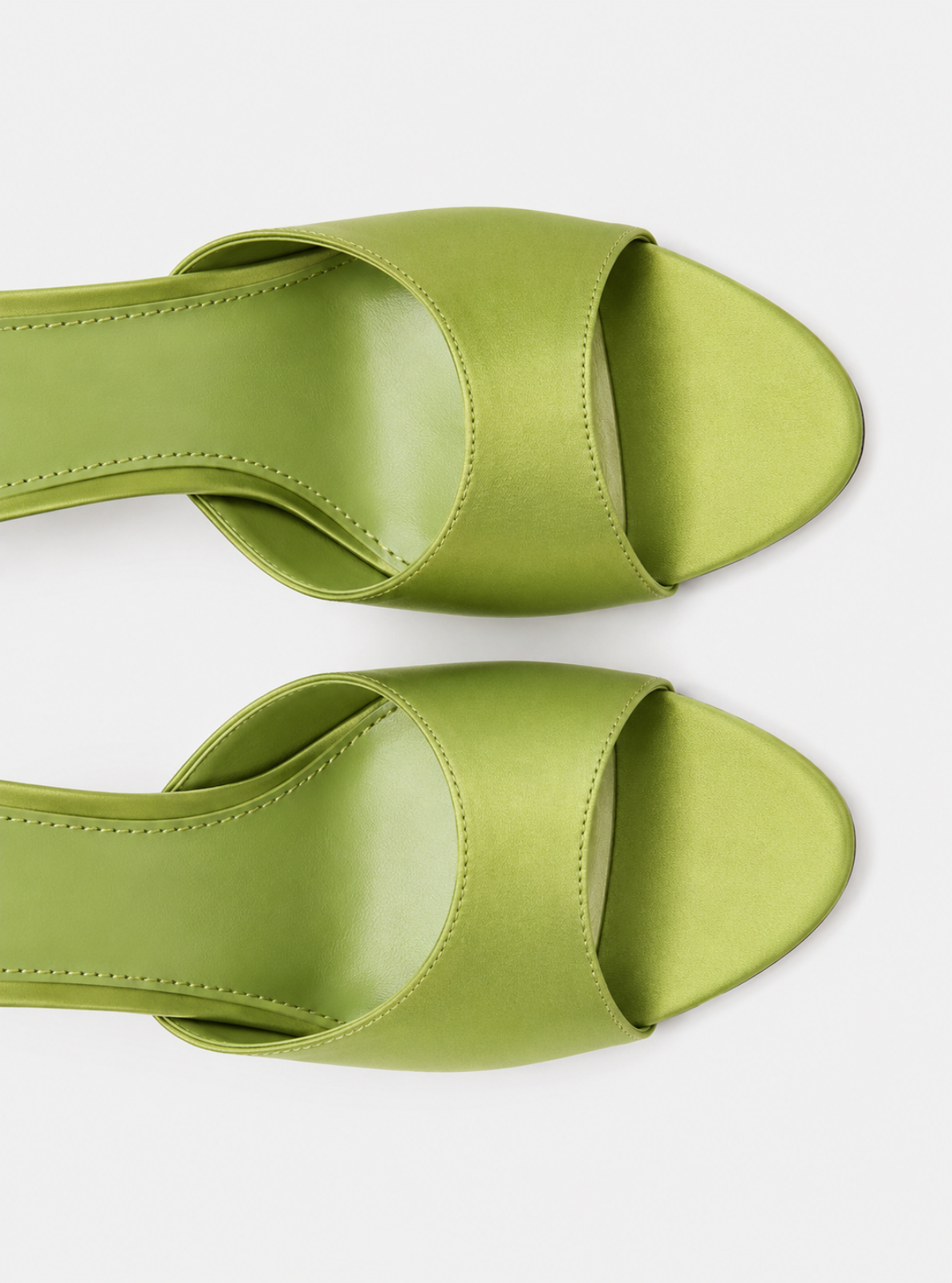 A pair of lime green open-toe slingback mule sandals with wide crisscross straps, shown from a top-down view on a light gray background.