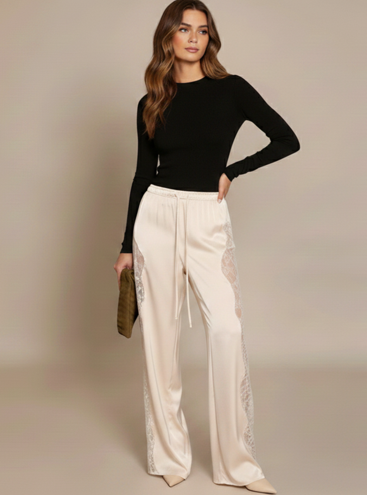Woman wearing a black top and white pants against a beige background