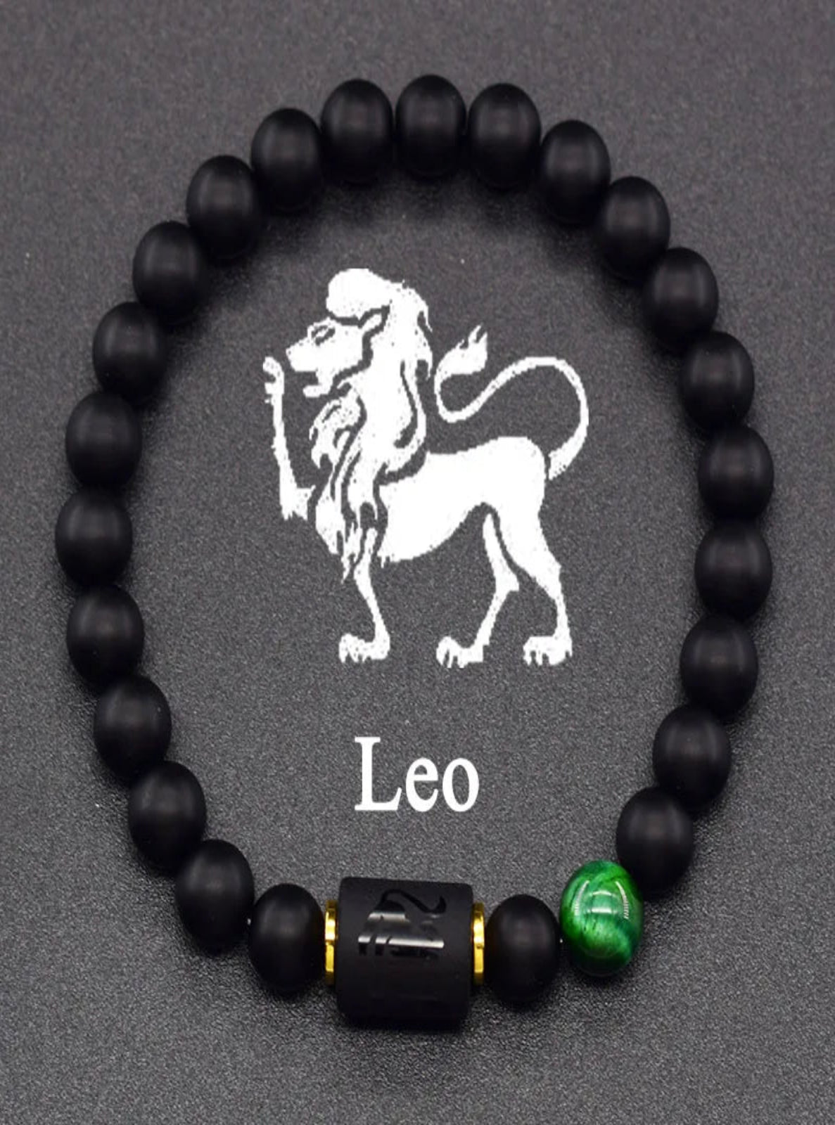 Black beaded bracelet with a Leo symbol and green accent bead on a gray background