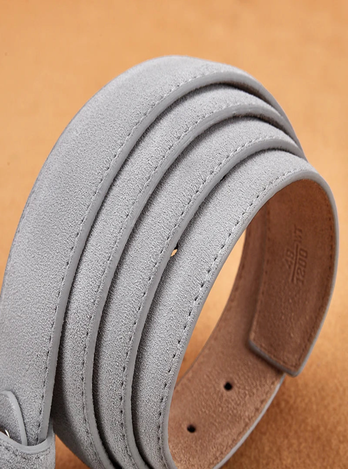 Gray suede belt with leather buckle on a brown background