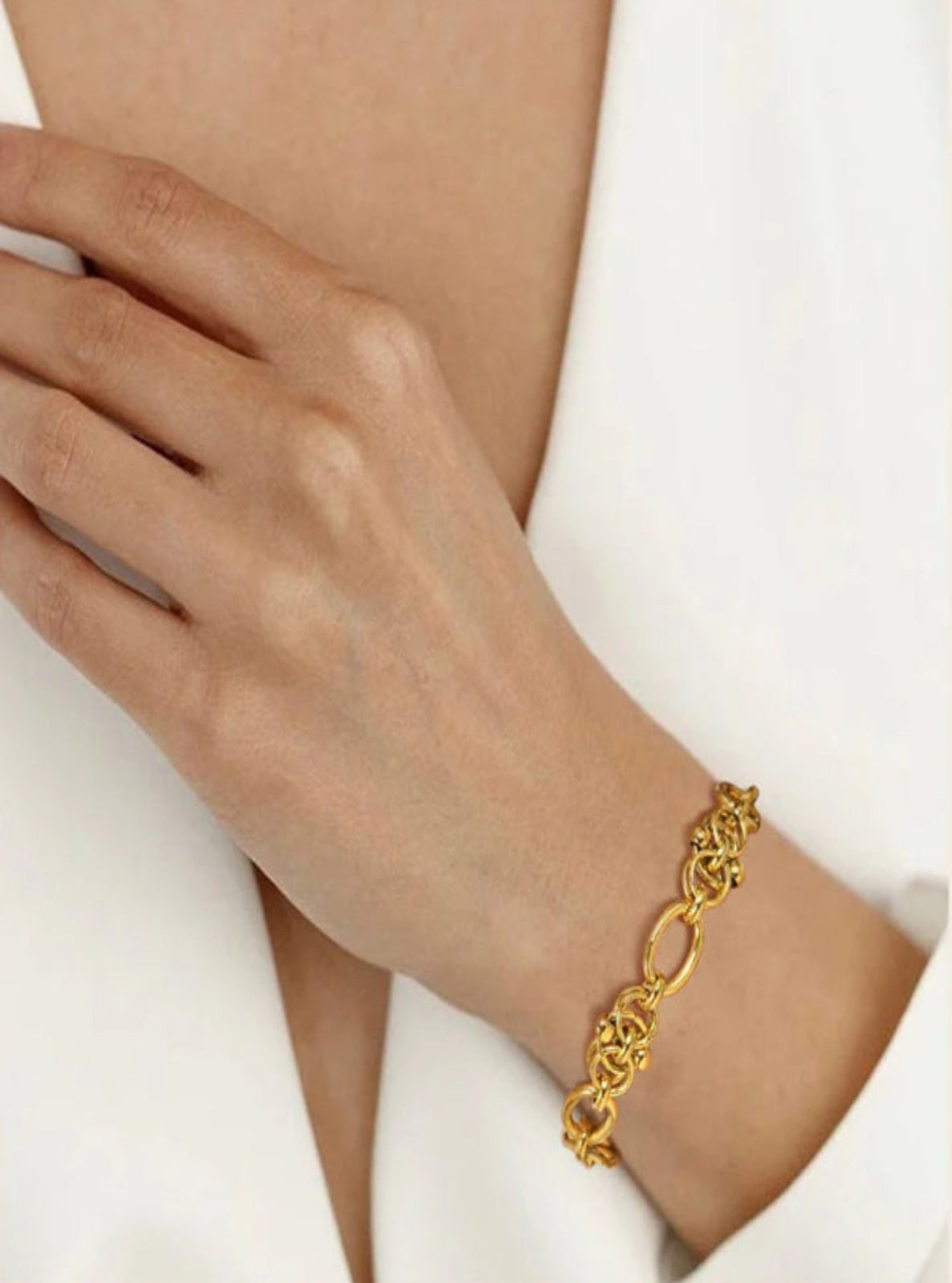 Gold bracelet on a wrist with a neutral background