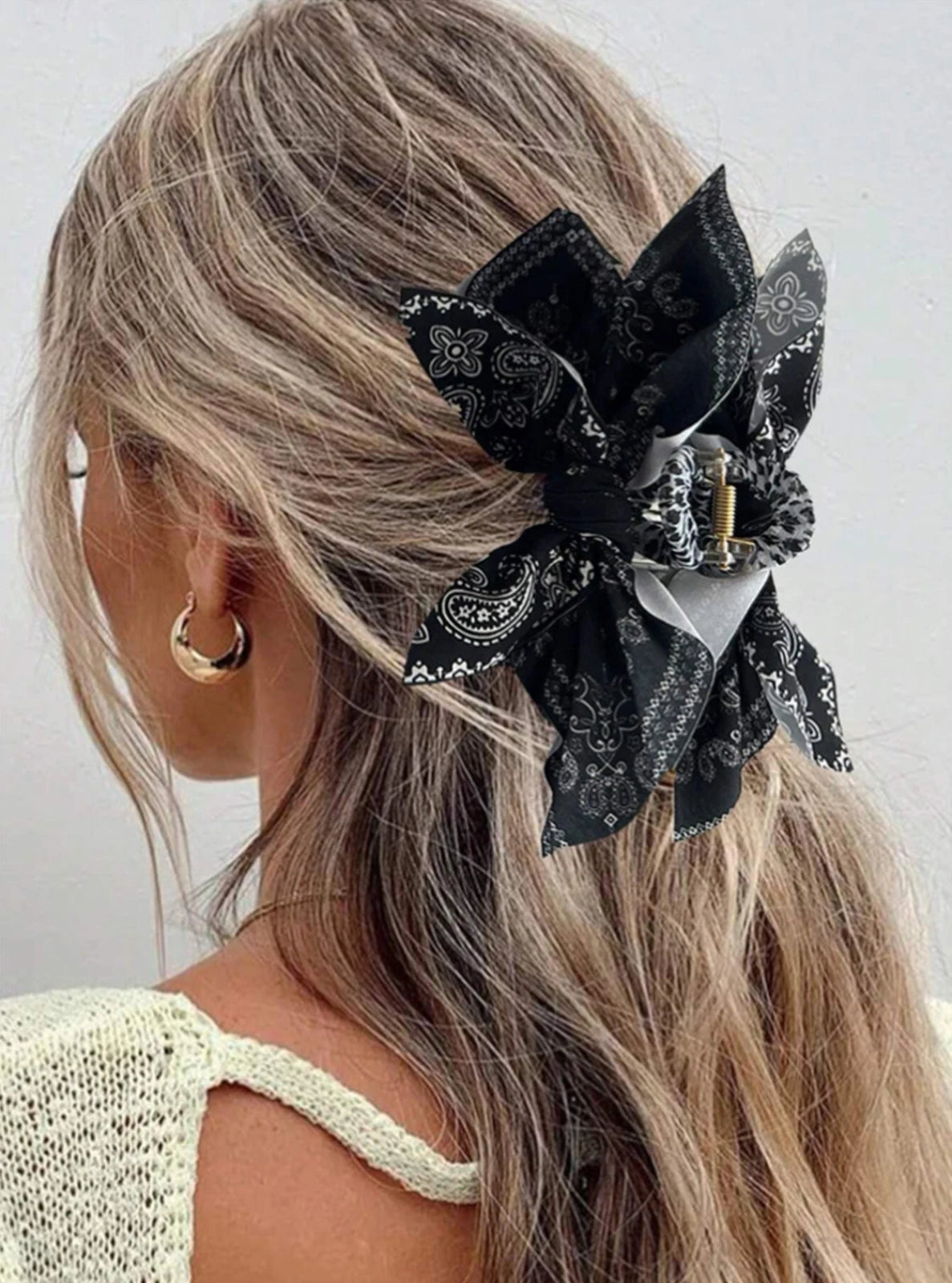 Woman with black floral hair accessory in her blonde hair against a white background