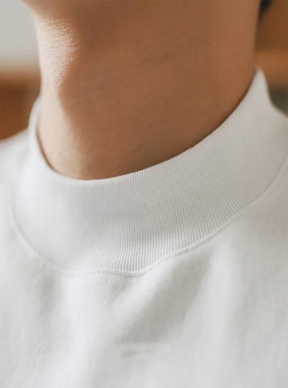 Close-up of a person wearing a white sweater with a blurred background