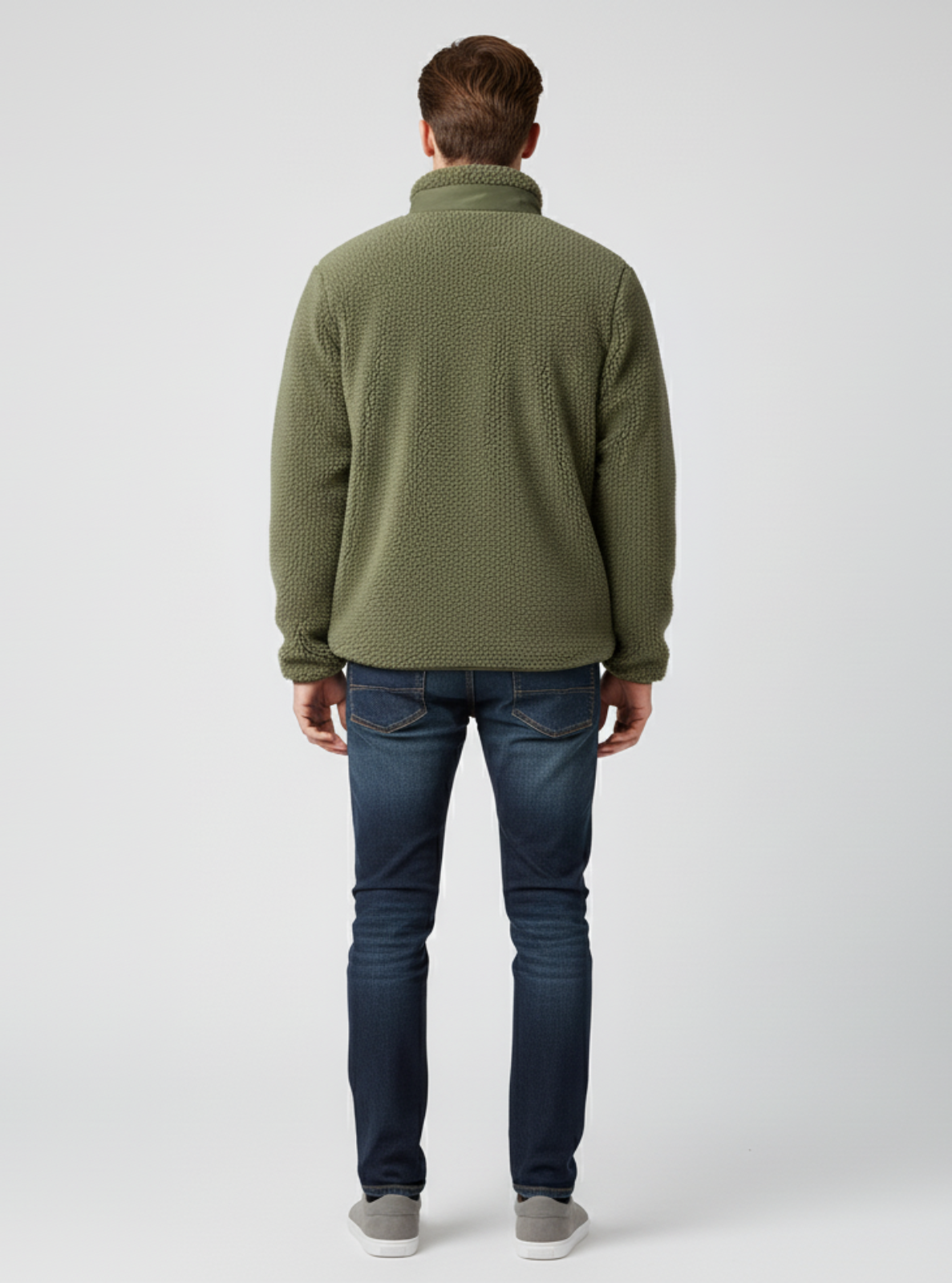 Man wearing a green textured sweater and blue jeans on a white background