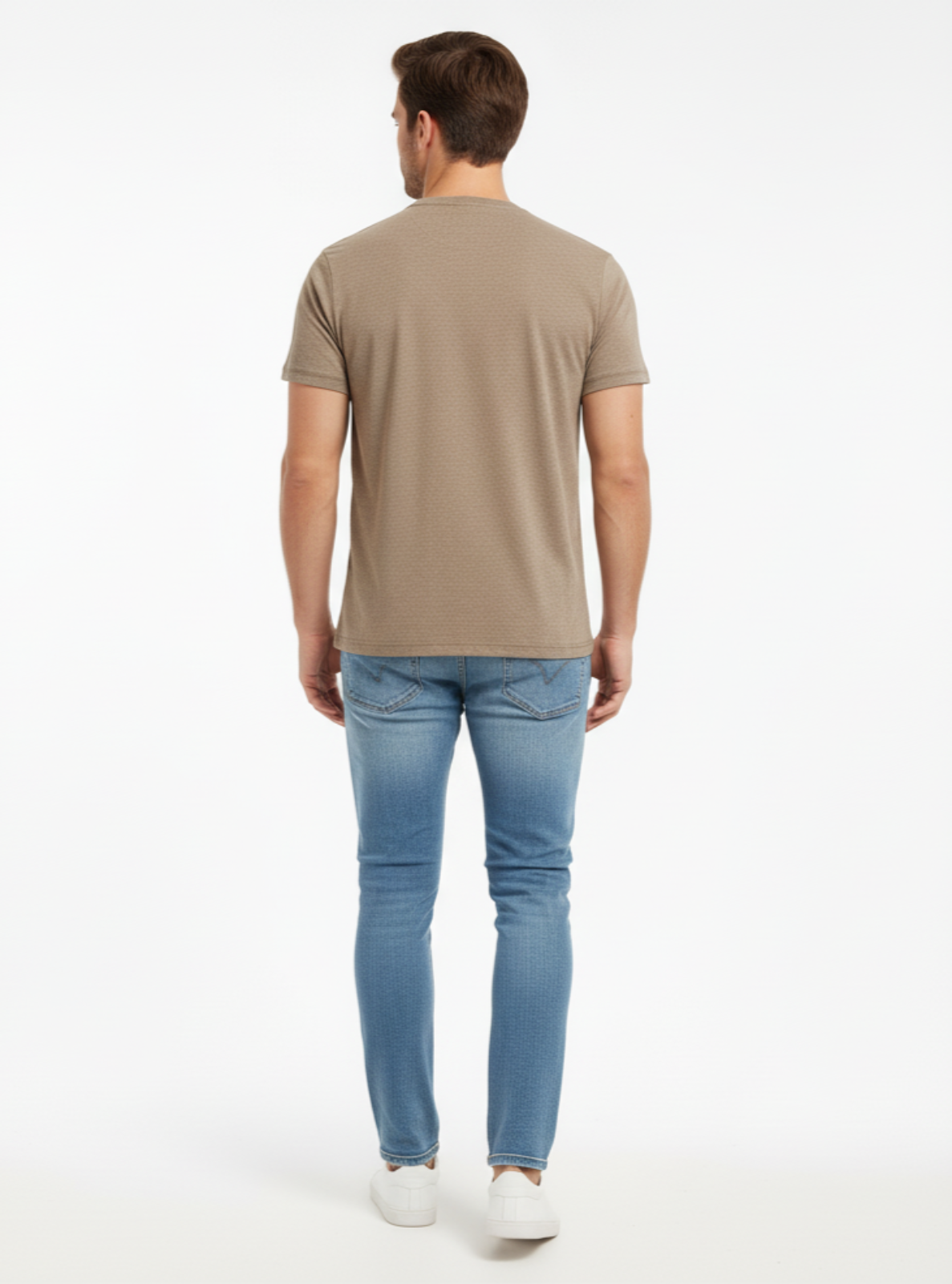 Man wearing a beige t-shirt and light blue jeans on a white background