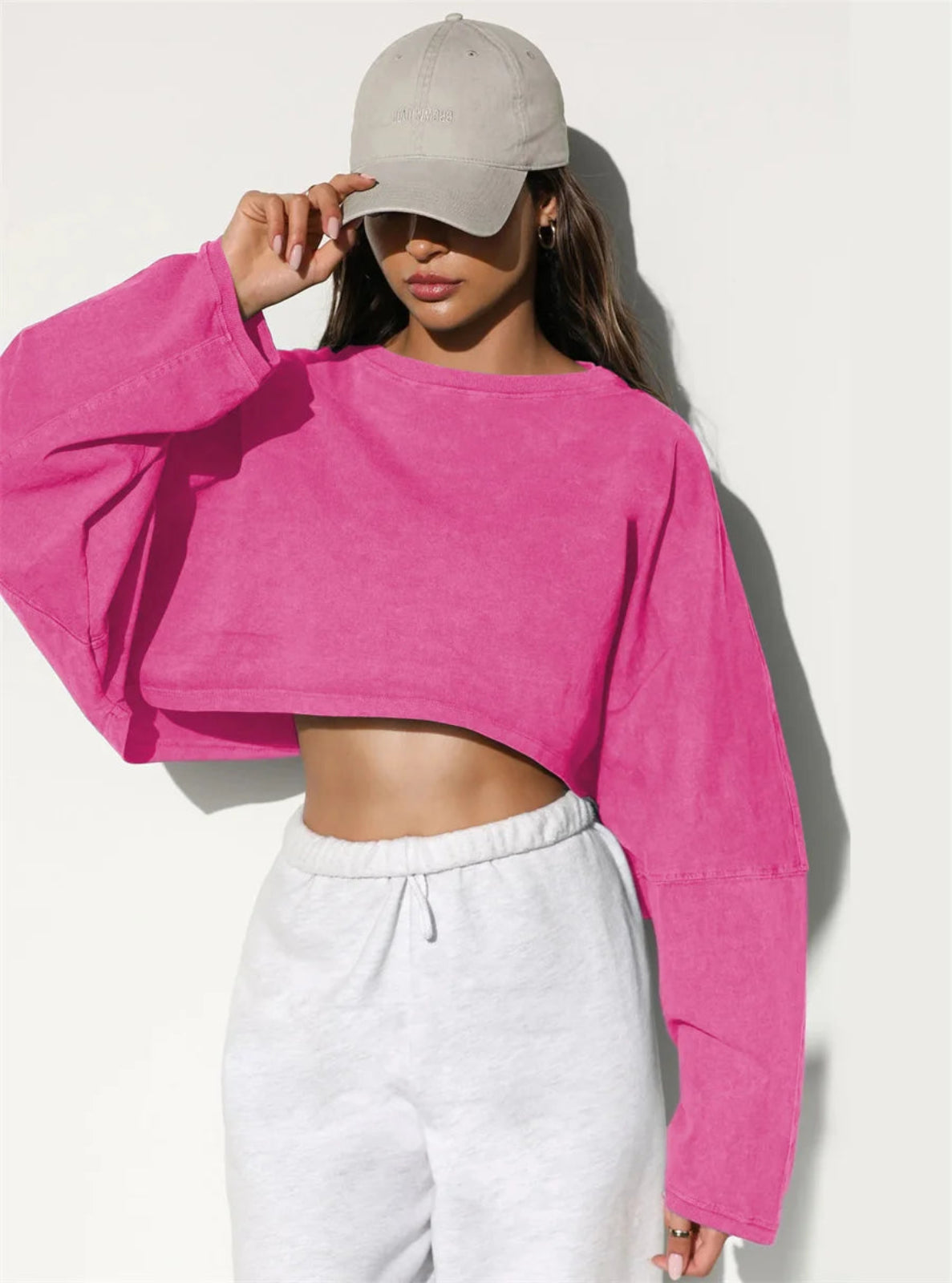 Person wearing a pink crop top and white pants against a white background