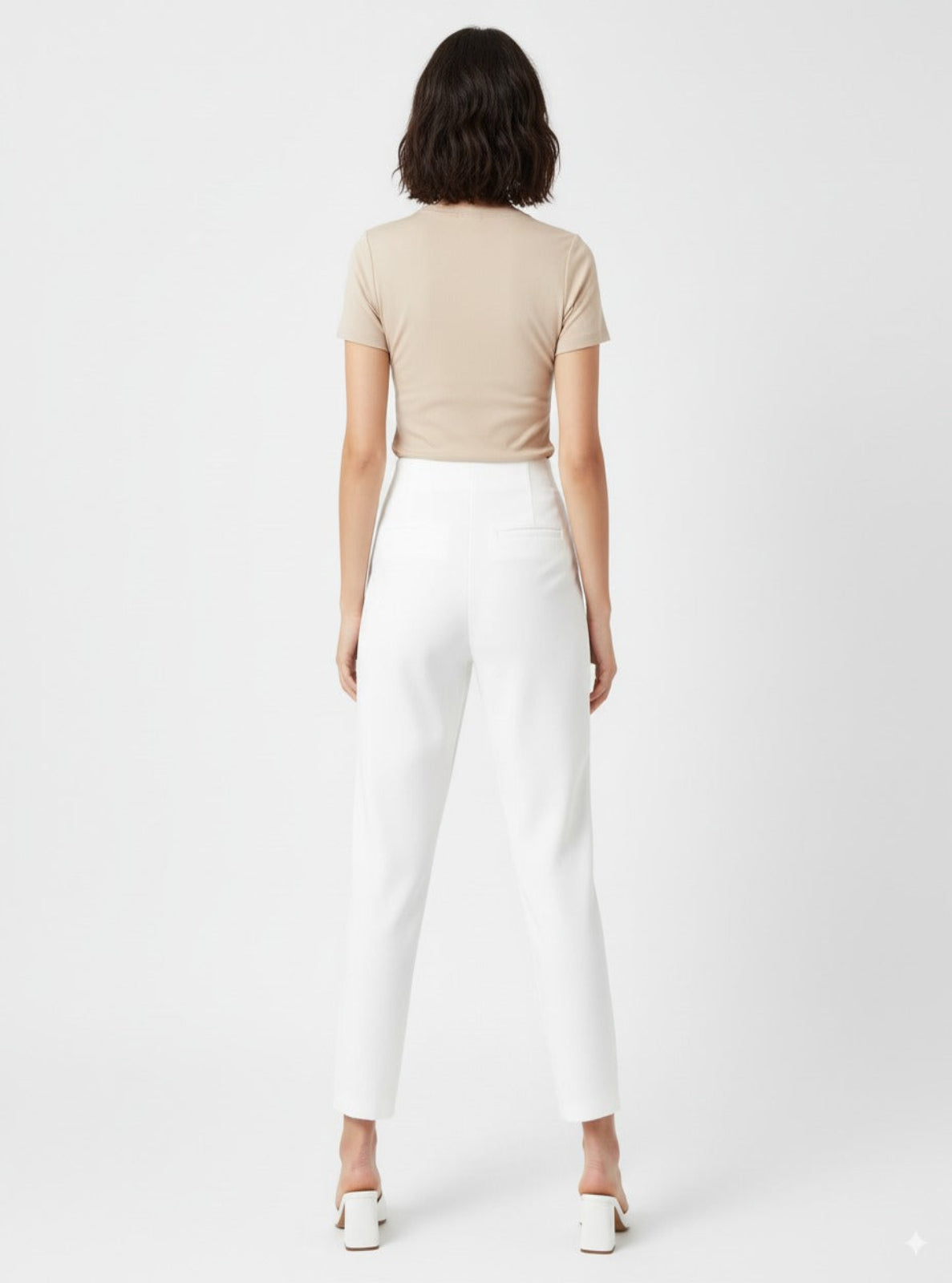 Person wearing a beige top and white pants on a plain background