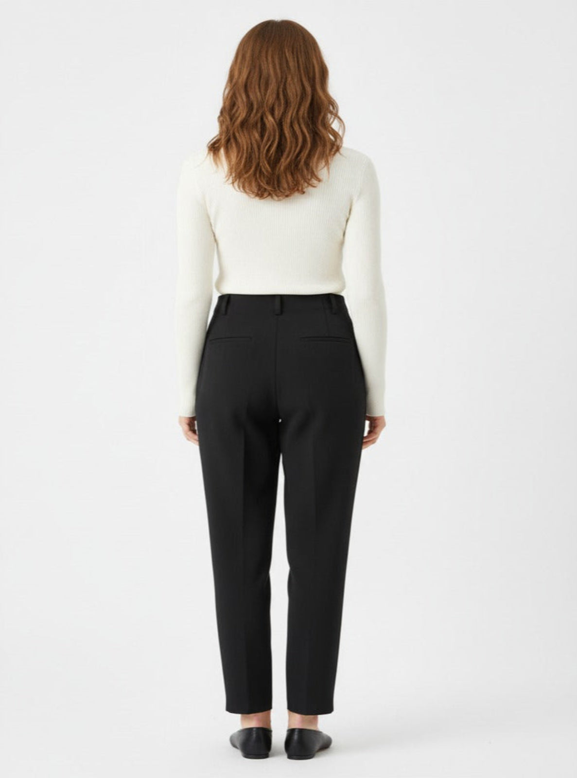 Woman wearing black pants and a white top on a white background