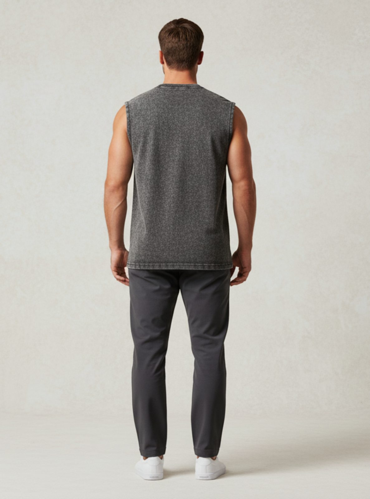 Man wearing a sleeveless gray shirt and pants on a plain background