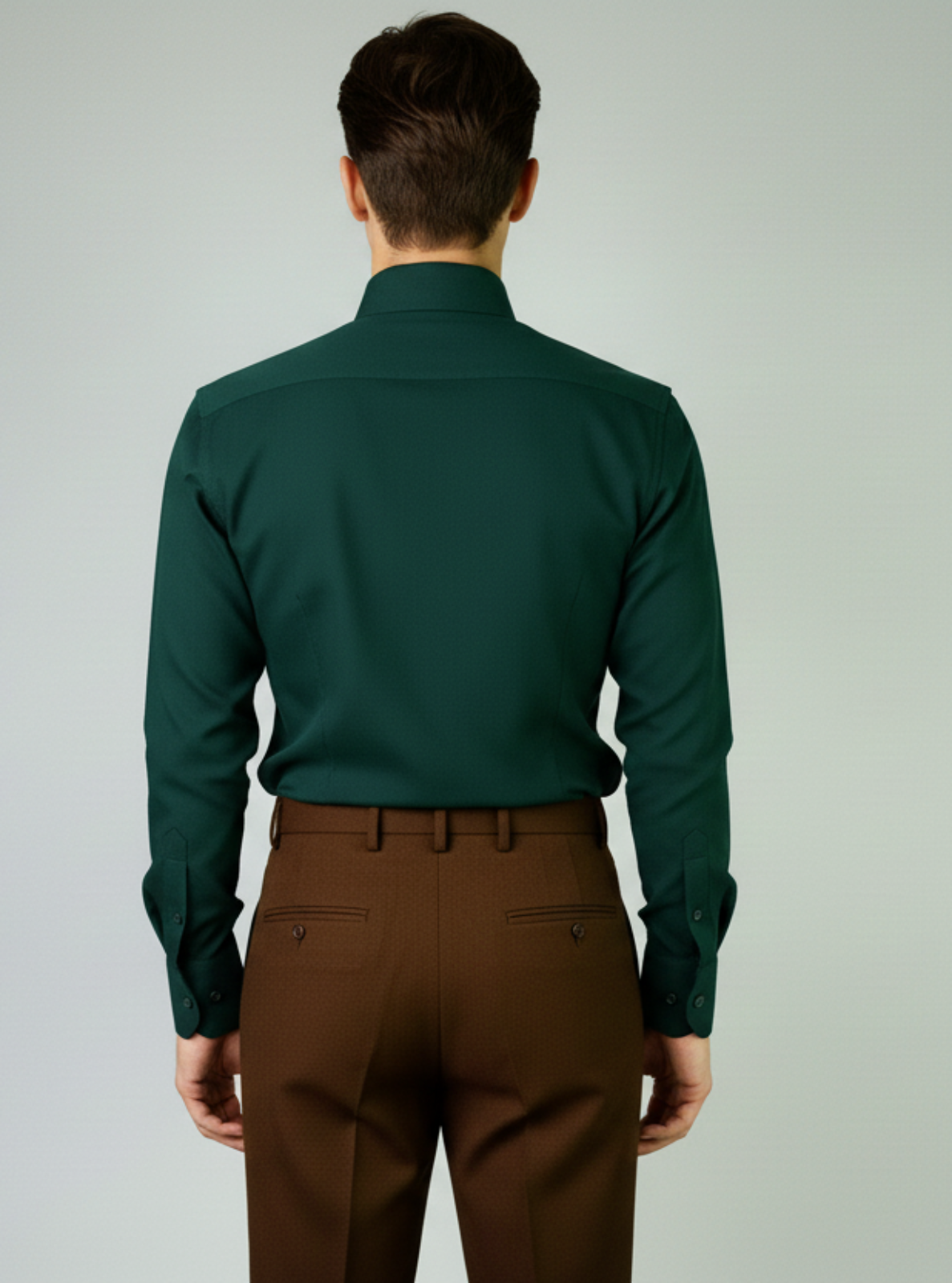 Man wearing a green shirt and brown pants on a plain background