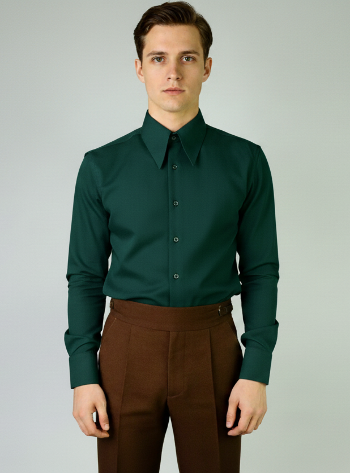 Man wearing a green dress shirt and brown pants against a gray background