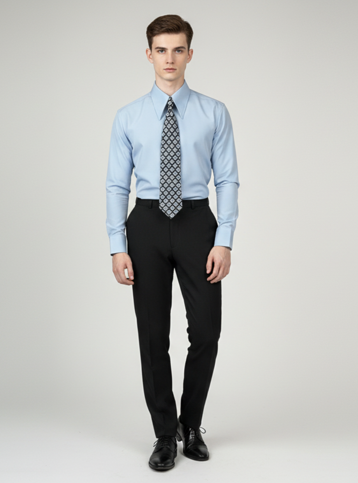 Man wearing a light blue dress shirt, black pants, and a patterned tie on a gray background