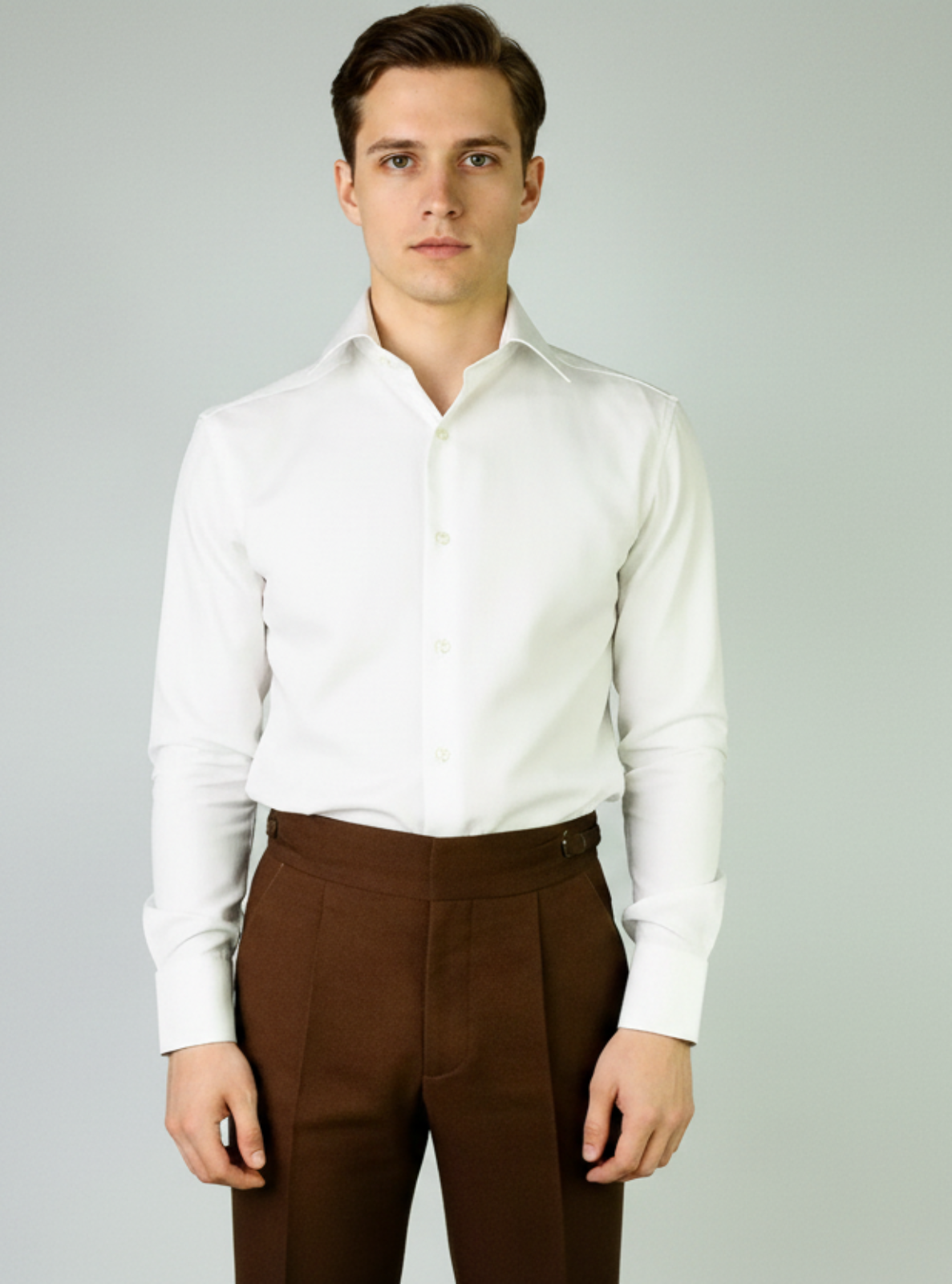 Man wearing a white dress shirt and brown pants on a gray background