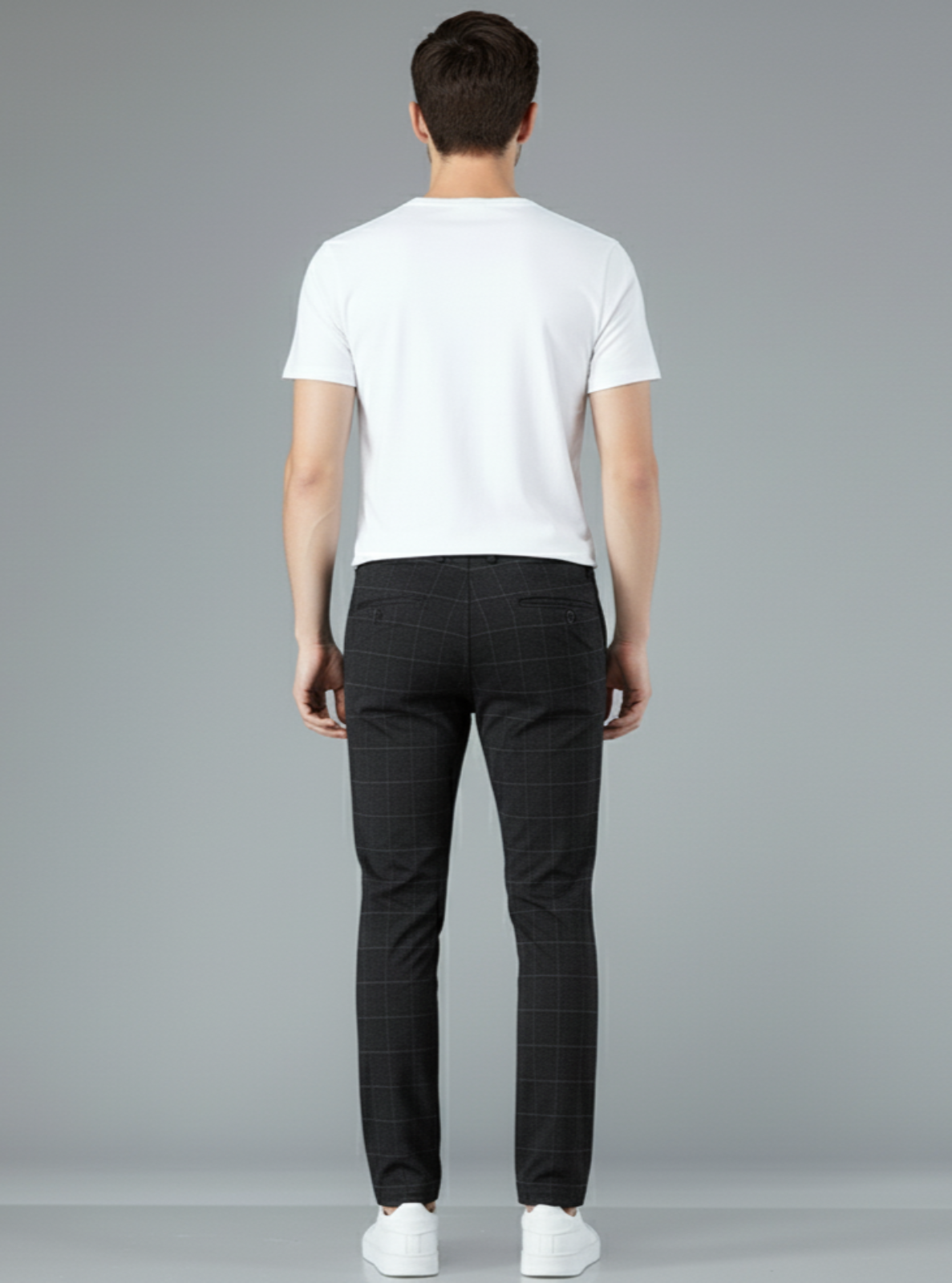 Man wearing a white t-shirt and black checkered pants on a gray background