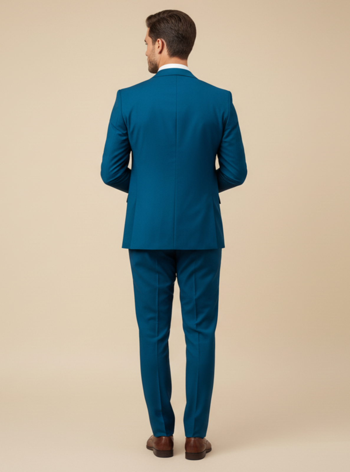Man wearing a teal suit standing against a beige background