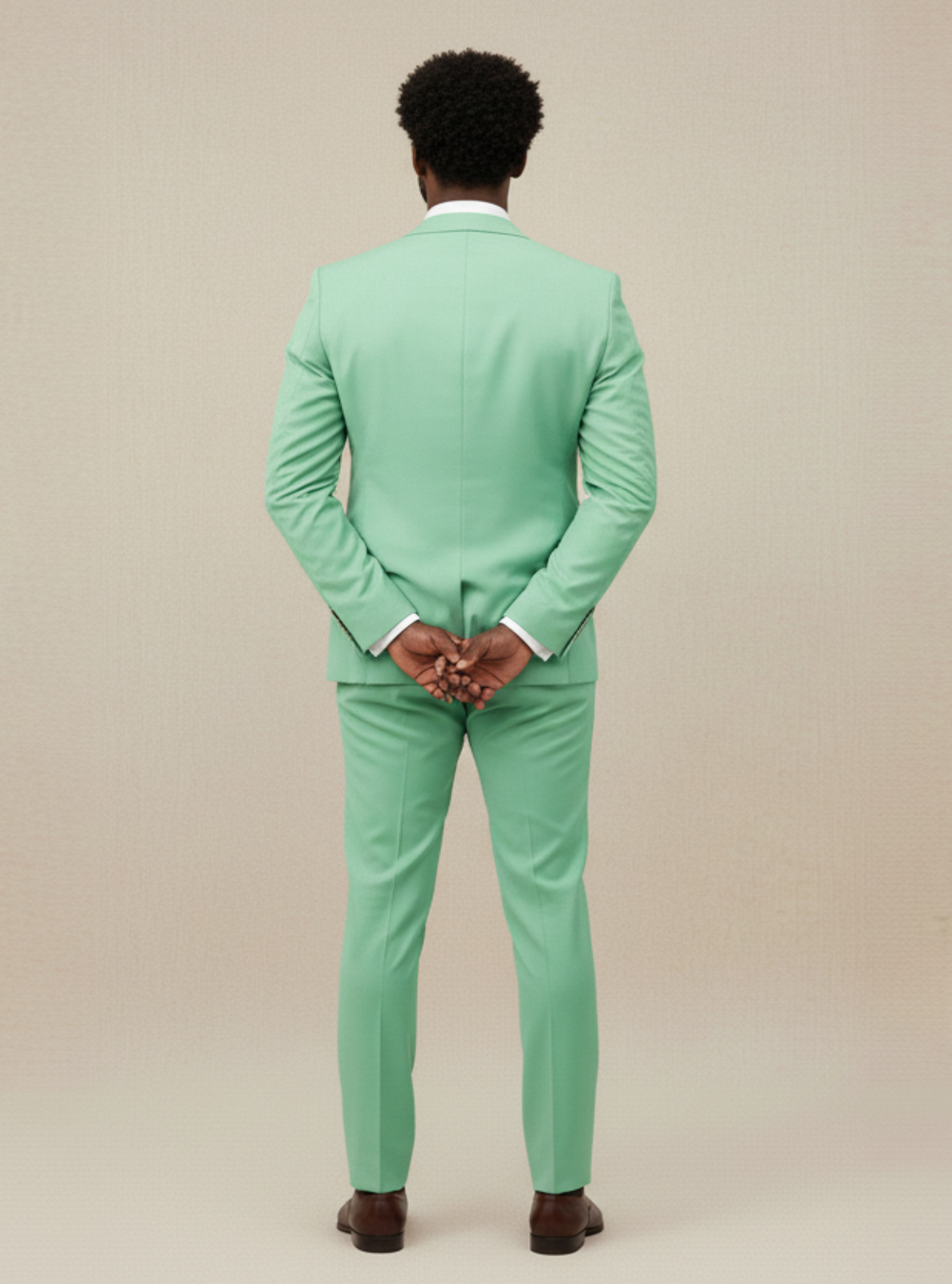 Man wearing a light green suit standing against a beige background