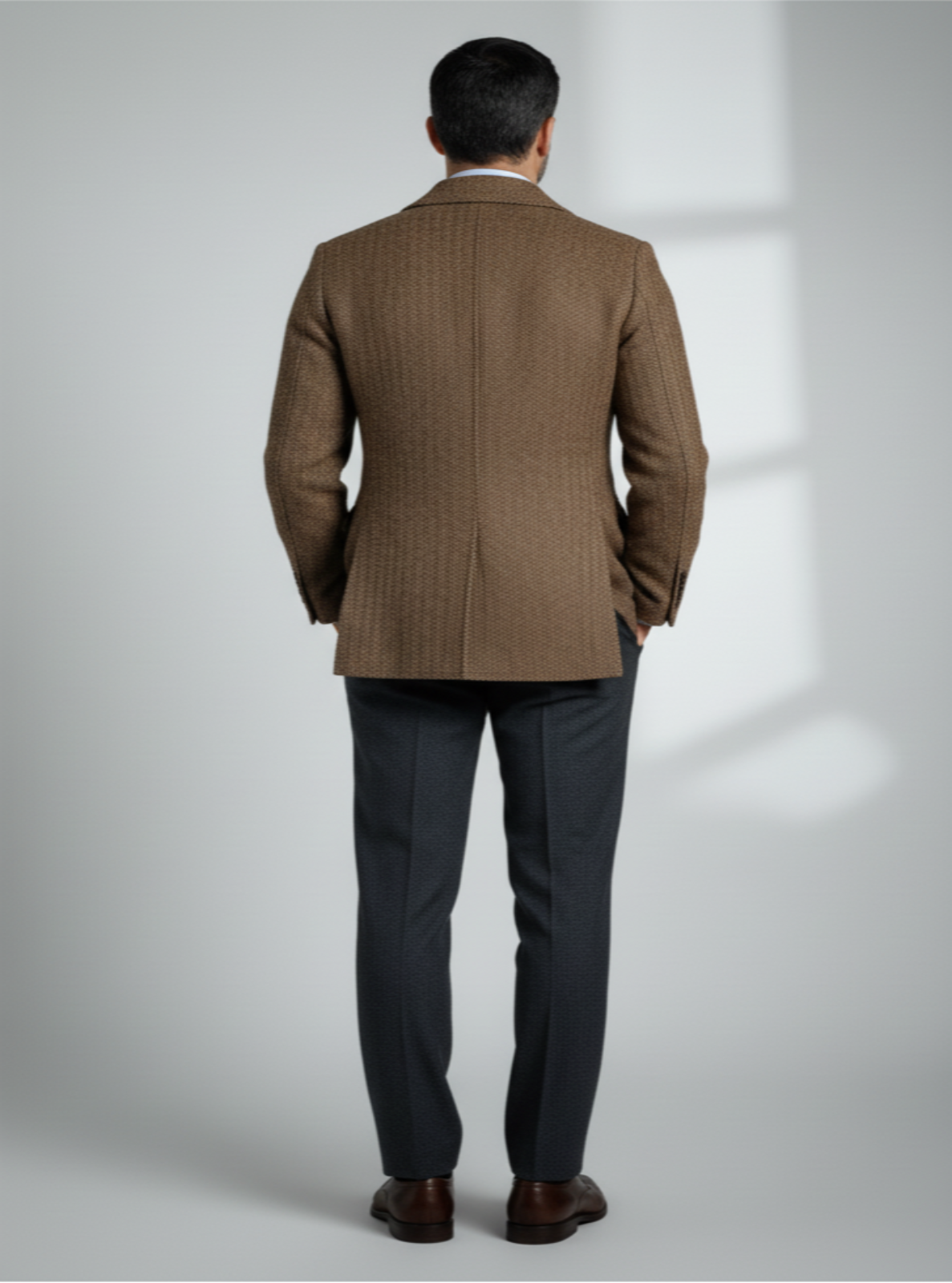 Man wearing a brown checkered suit against a light gray background