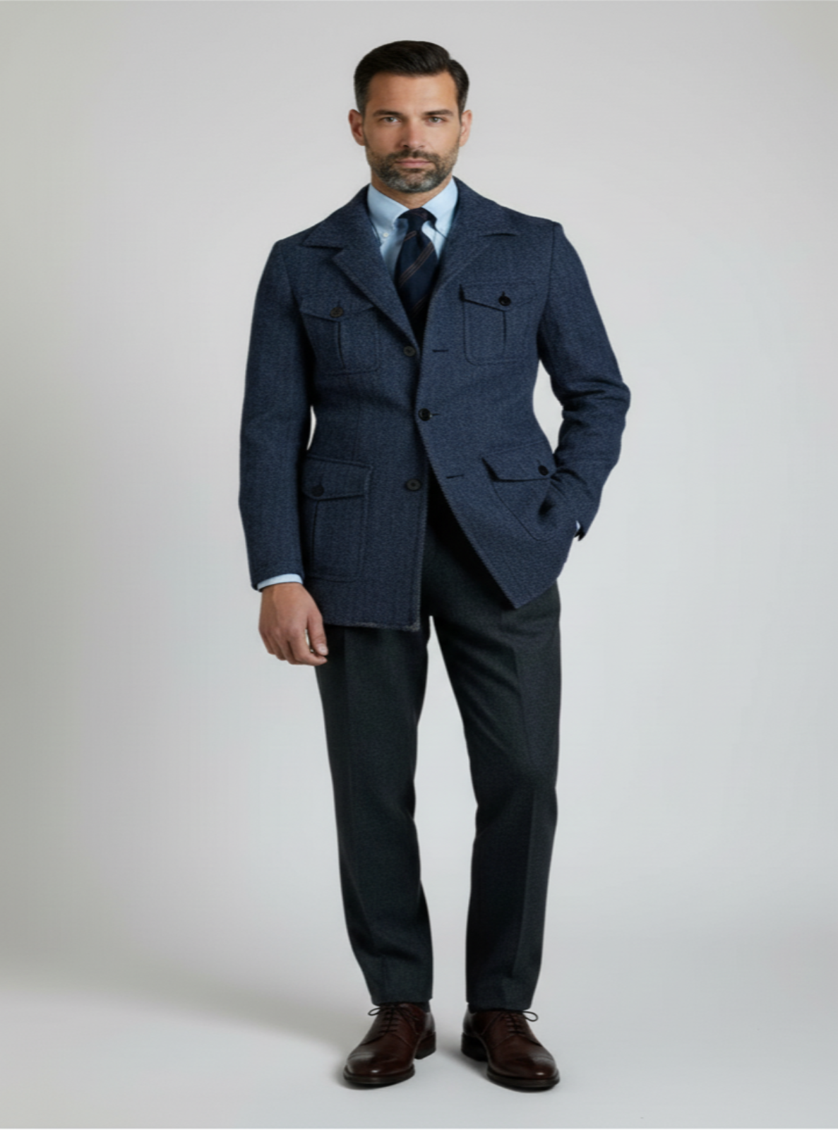 Man wearing a navy suit with a white shirt and brown shoes on a light gray background