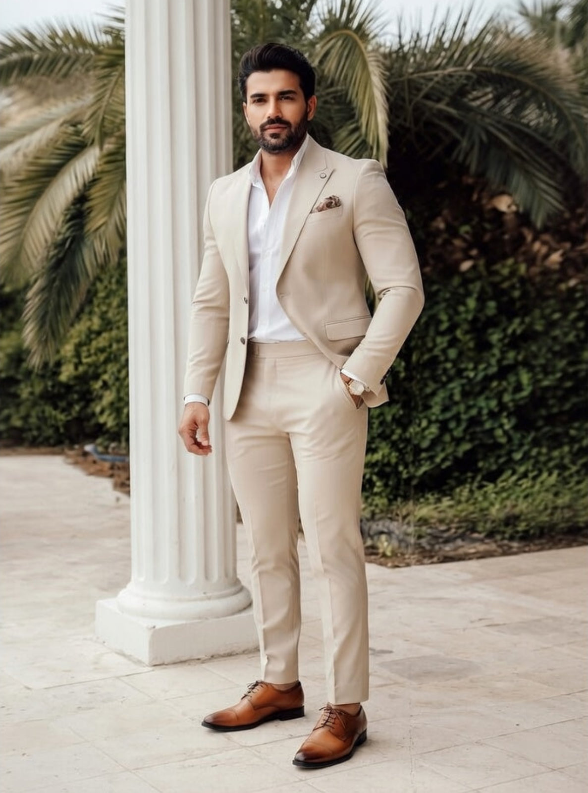 Man in a beige suit standing outdoors with columns and greenery in the background
