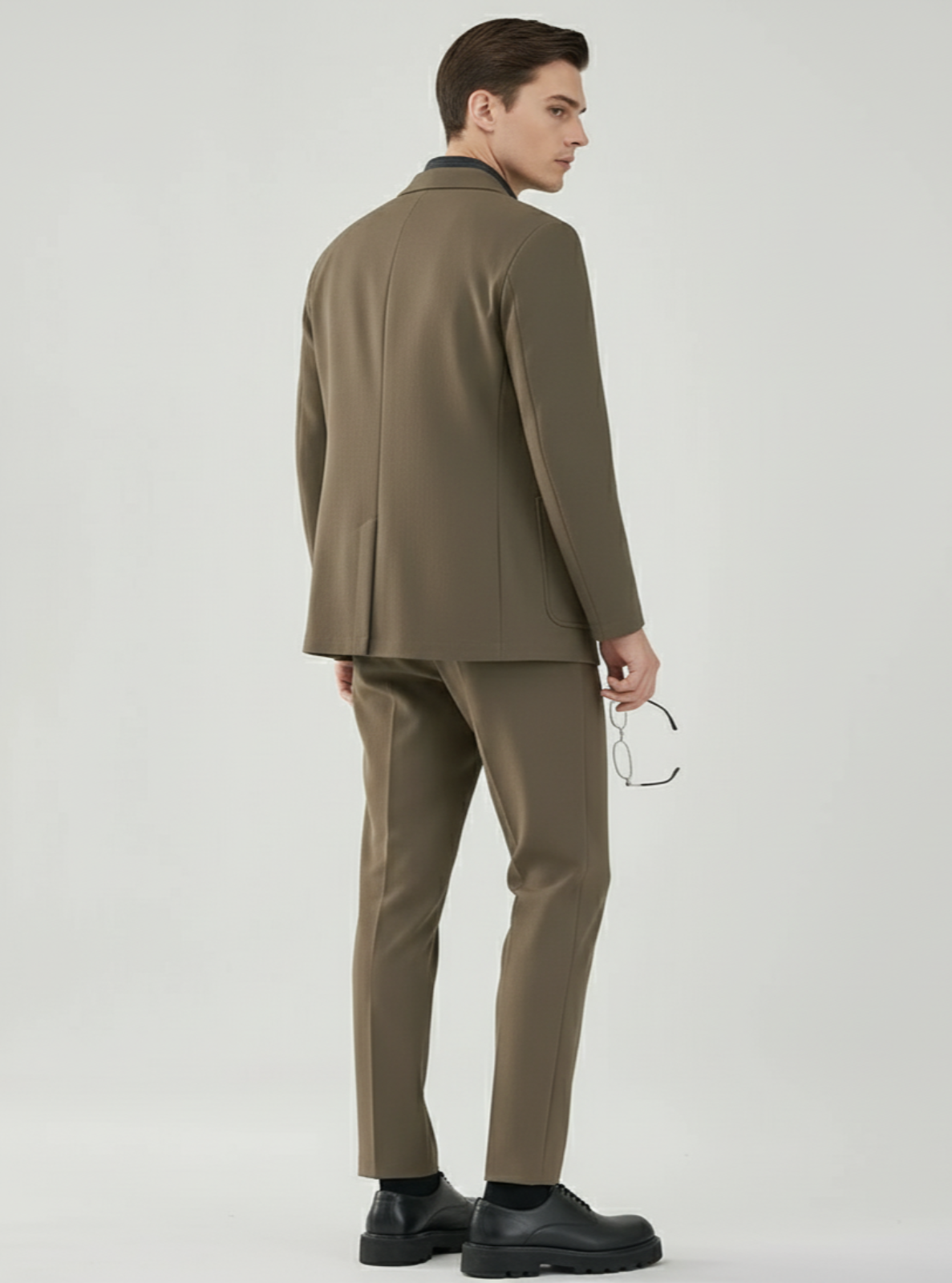 Man wearing a brown suit standing against a white background
