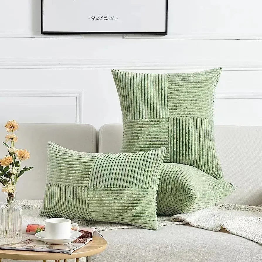 Green textured pillows on a sofa with a cup and flowers in the foreground