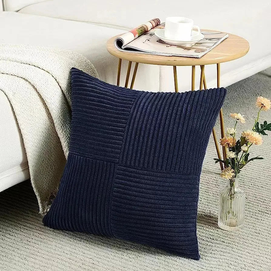 Navy blue textured pillow on a couch with a side table and flowers in the background