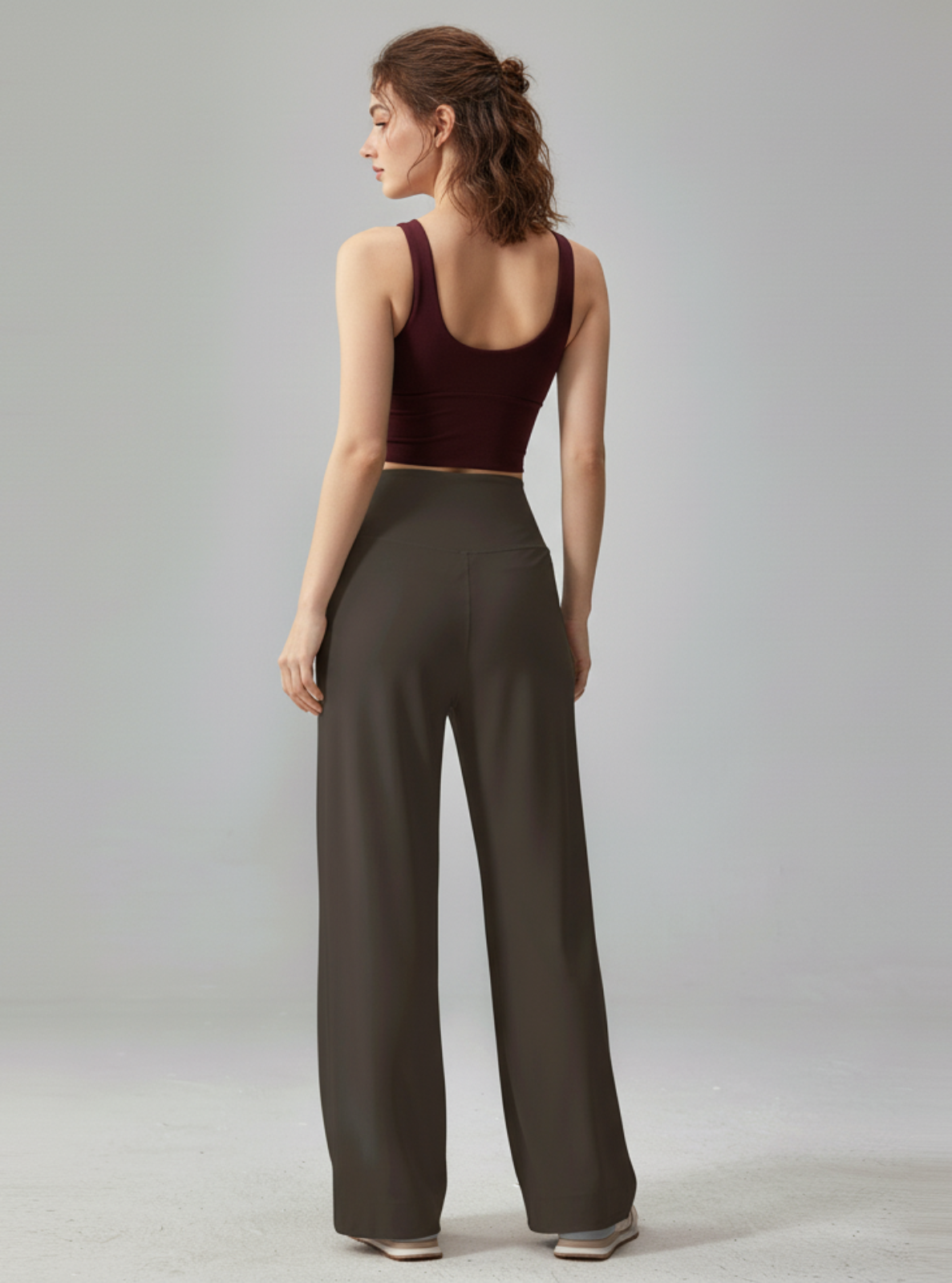 Woman wearing a burgundy top and dark green wide-leg pants on a plain background