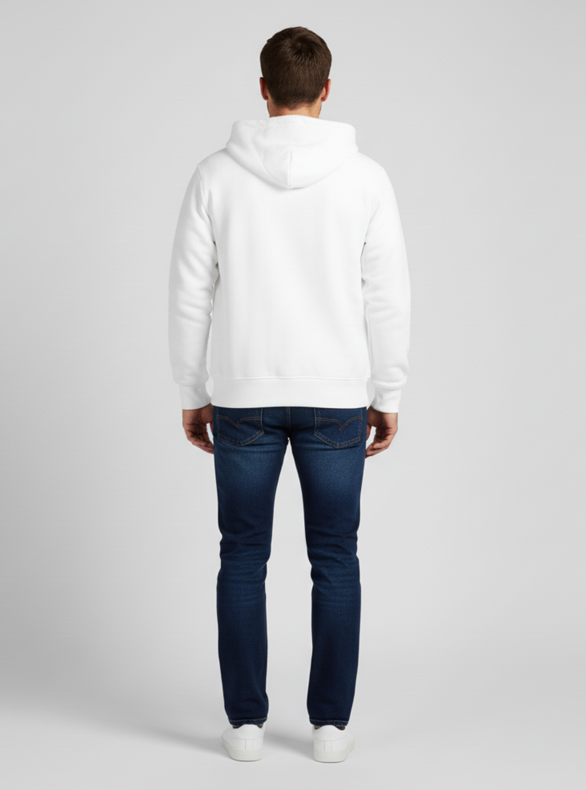 Person wearing a white hoodie and dark jeans on a gray background
