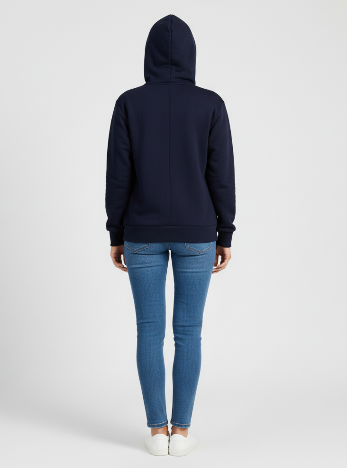 Person wearing a navy hoodie and blue jeans on a white background