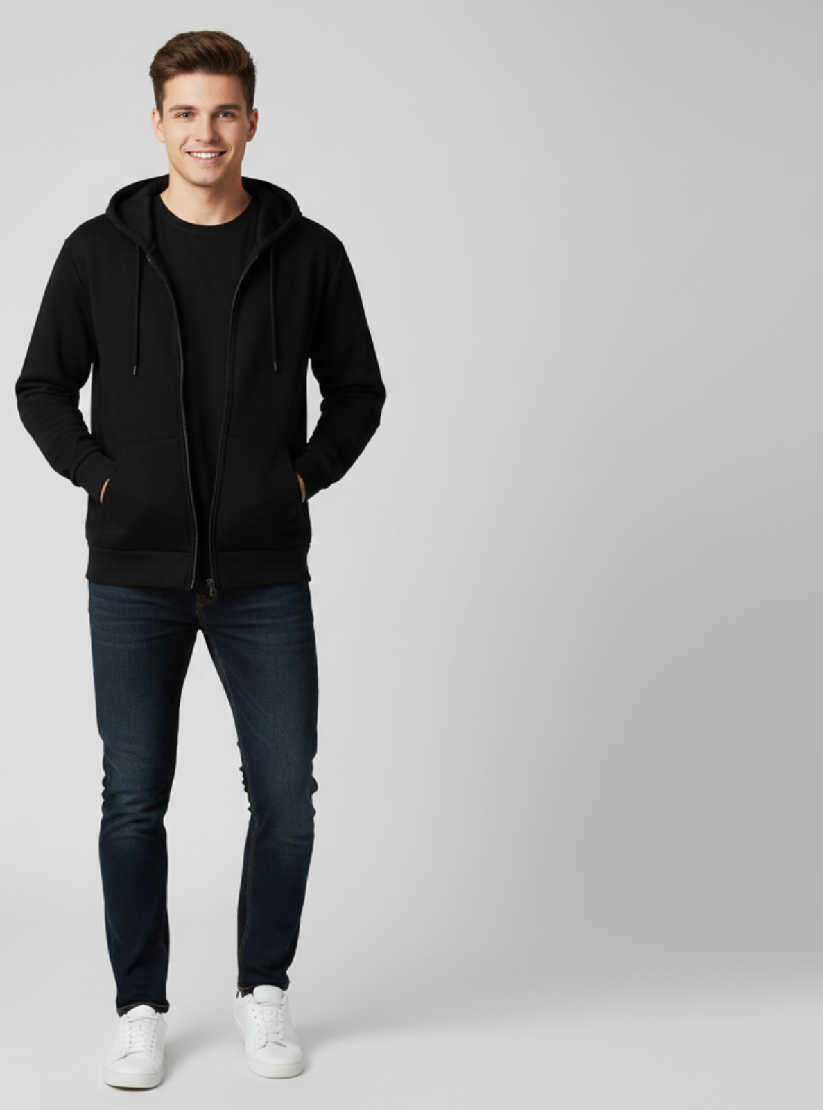 Man wearing a black hoodie, black t-shirt, dark jeans, and white sneakers on a light gray background