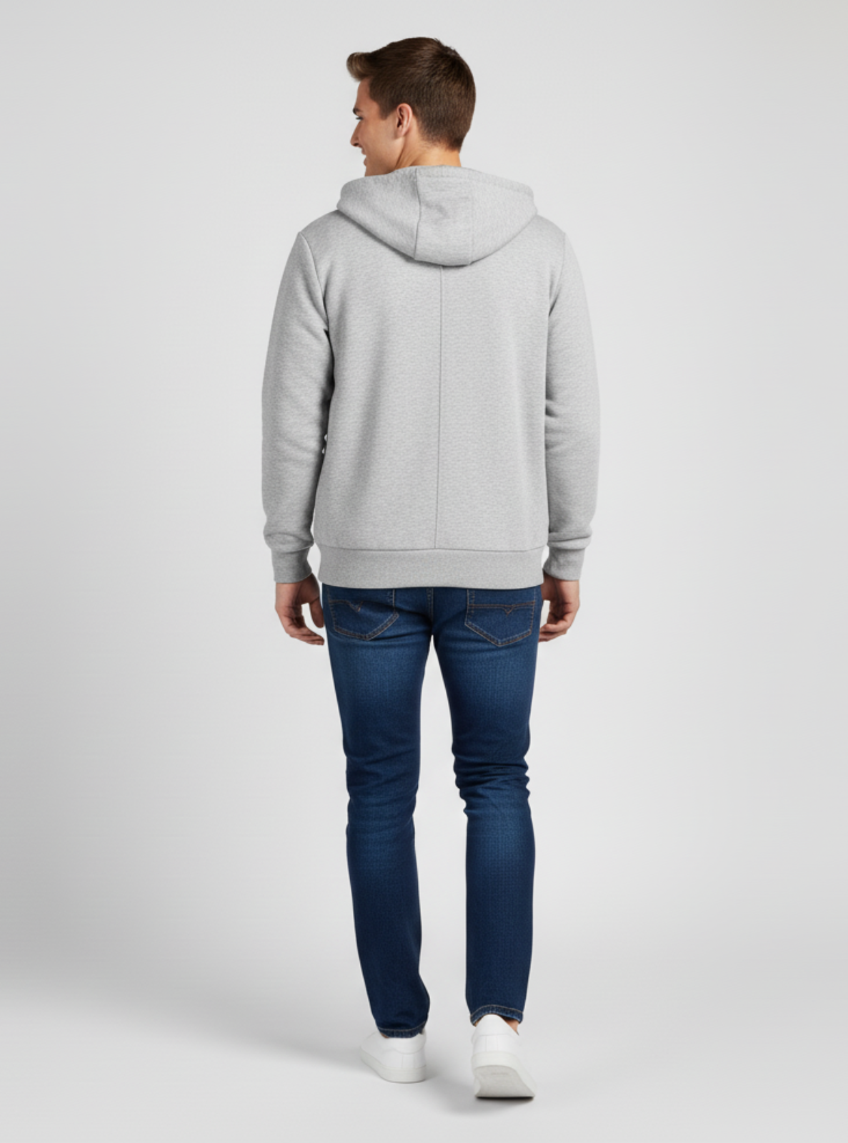 Person wearing a gray hoodie and blue jeans on a light gray background