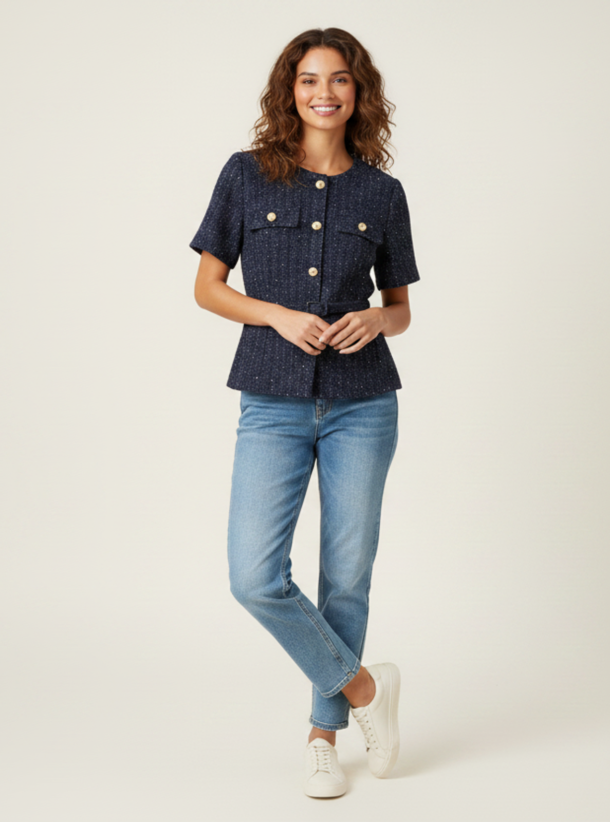 Woman wearing a navy shirt and light blue jeans on a white background