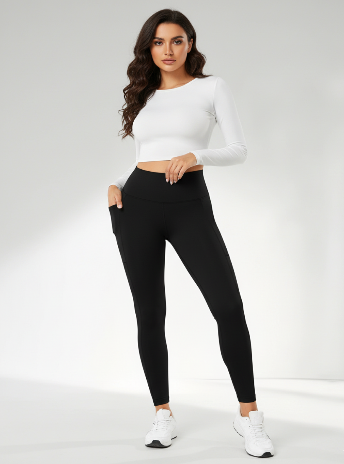 Woman wearing a white long-sleeve top and black leggings on a white background