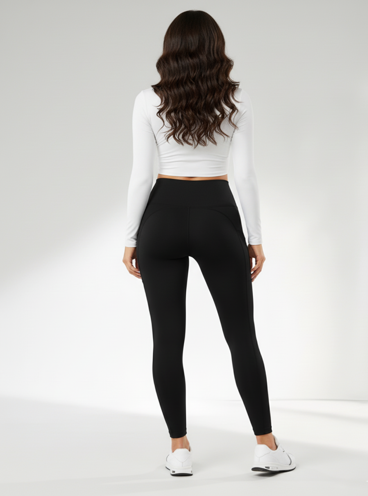 Person wearing black leggings and a white long-sleeve top on a white background