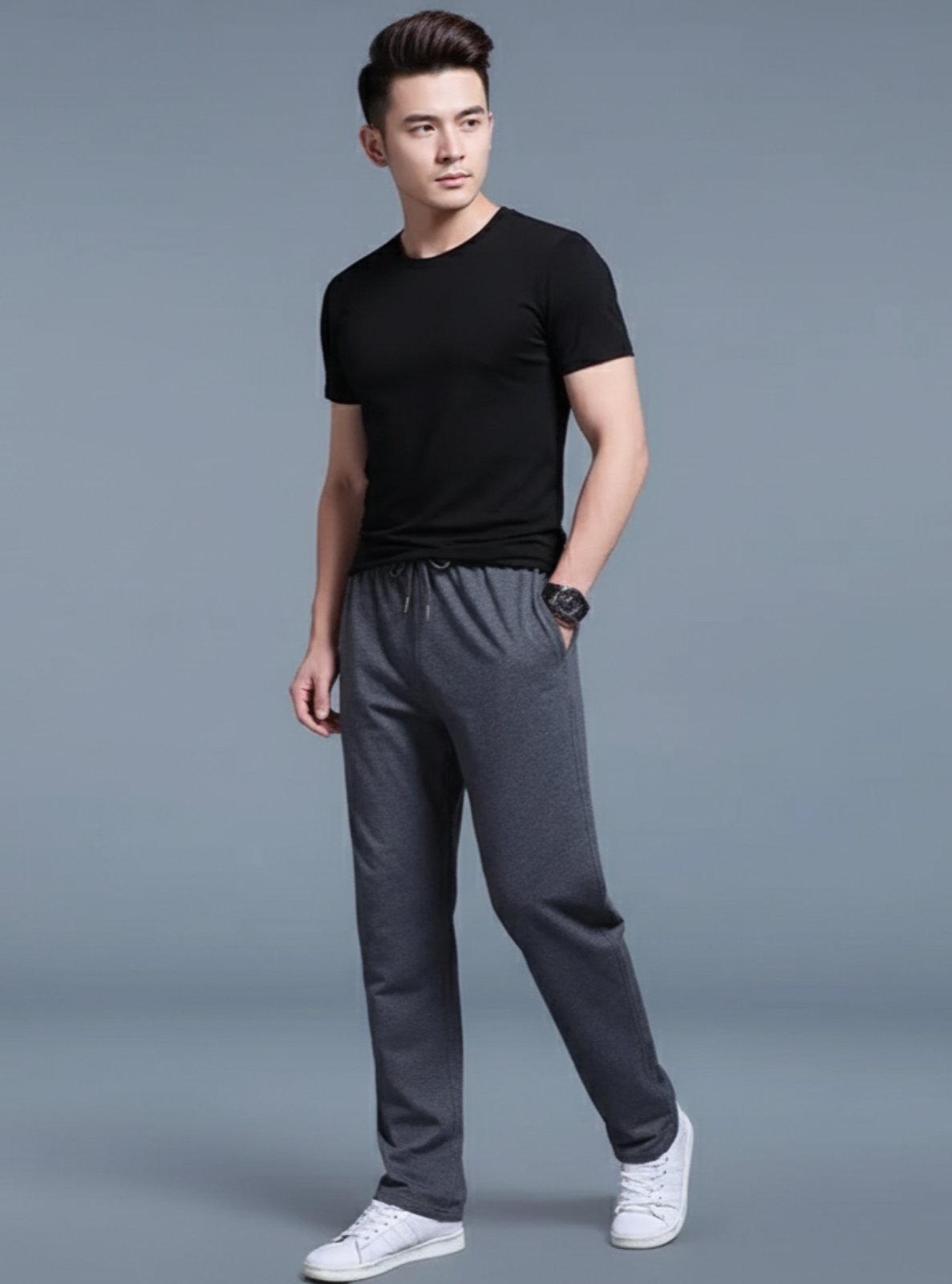 Man wearing a black t-shirt and gray pants on a gray background