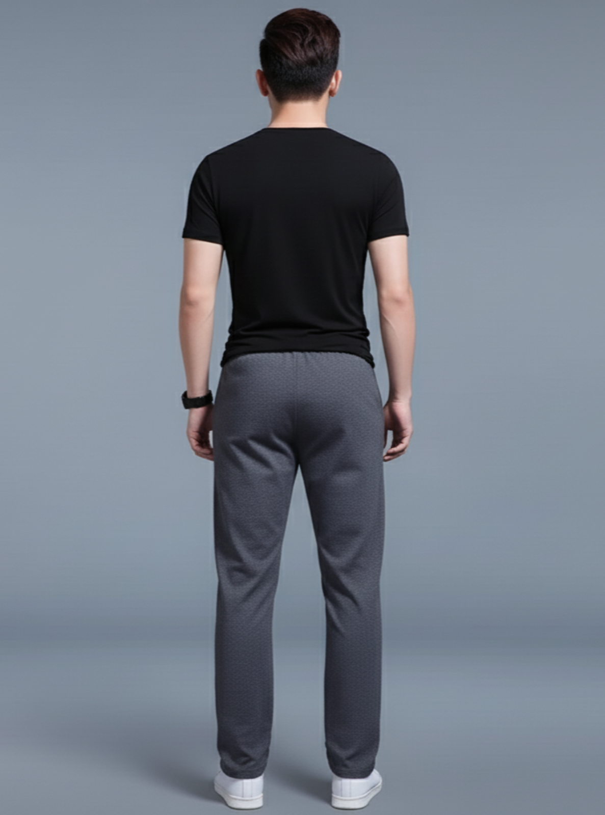 Man wearing a black t-shirt and gray pants on a gray background