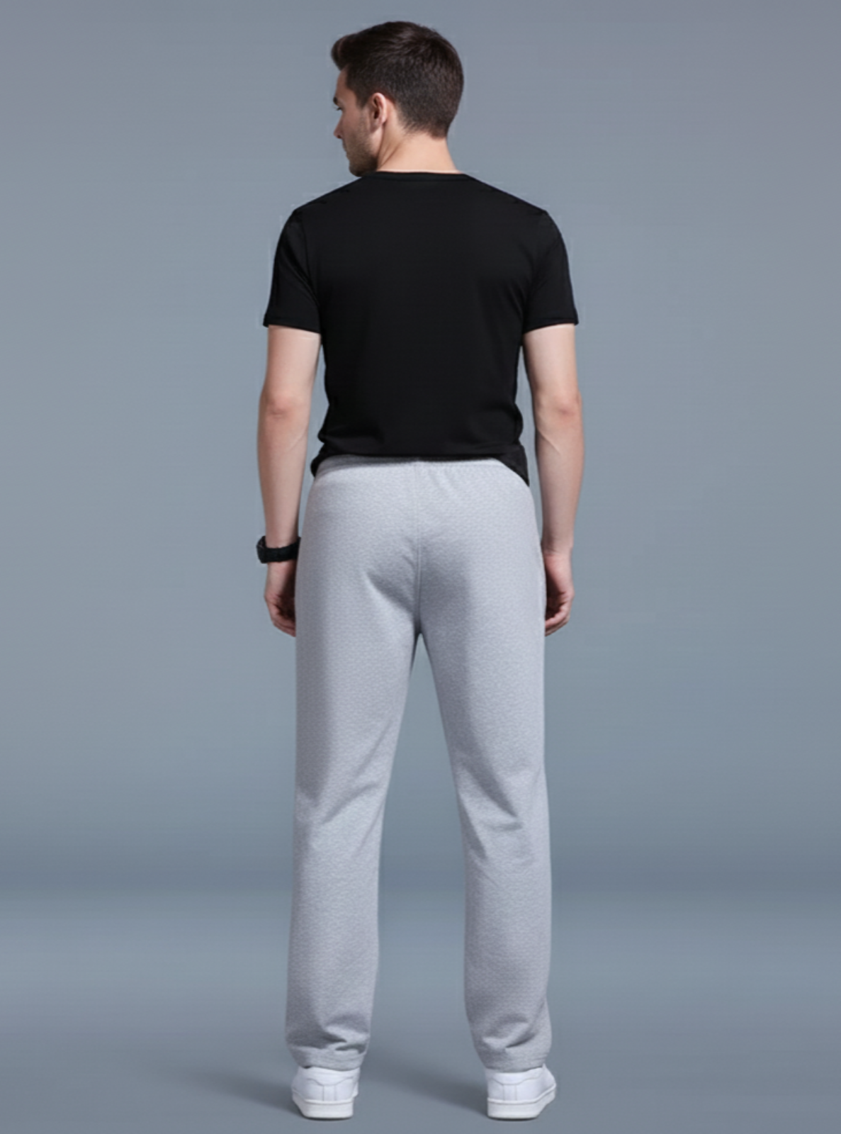 Man wearing a black t-shirt and gray sweatpants on a plain background