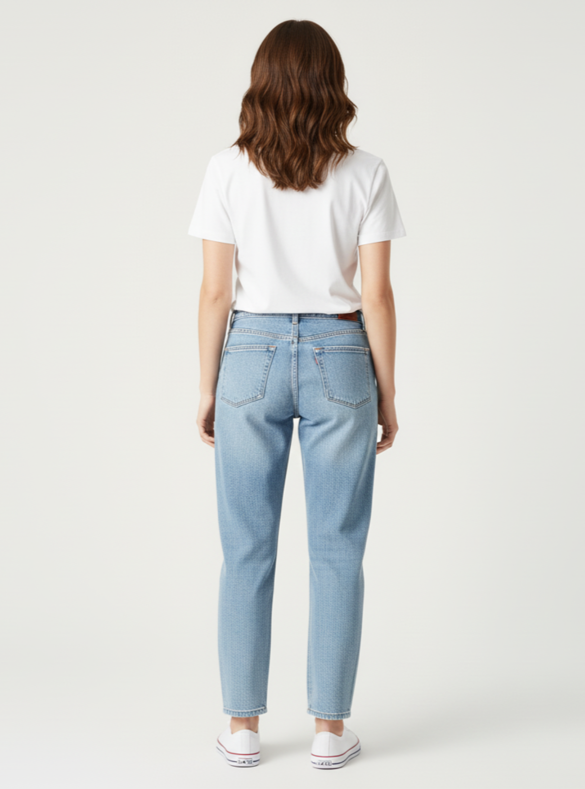 Person wearing light blue jeans and a white shirt on a plain background