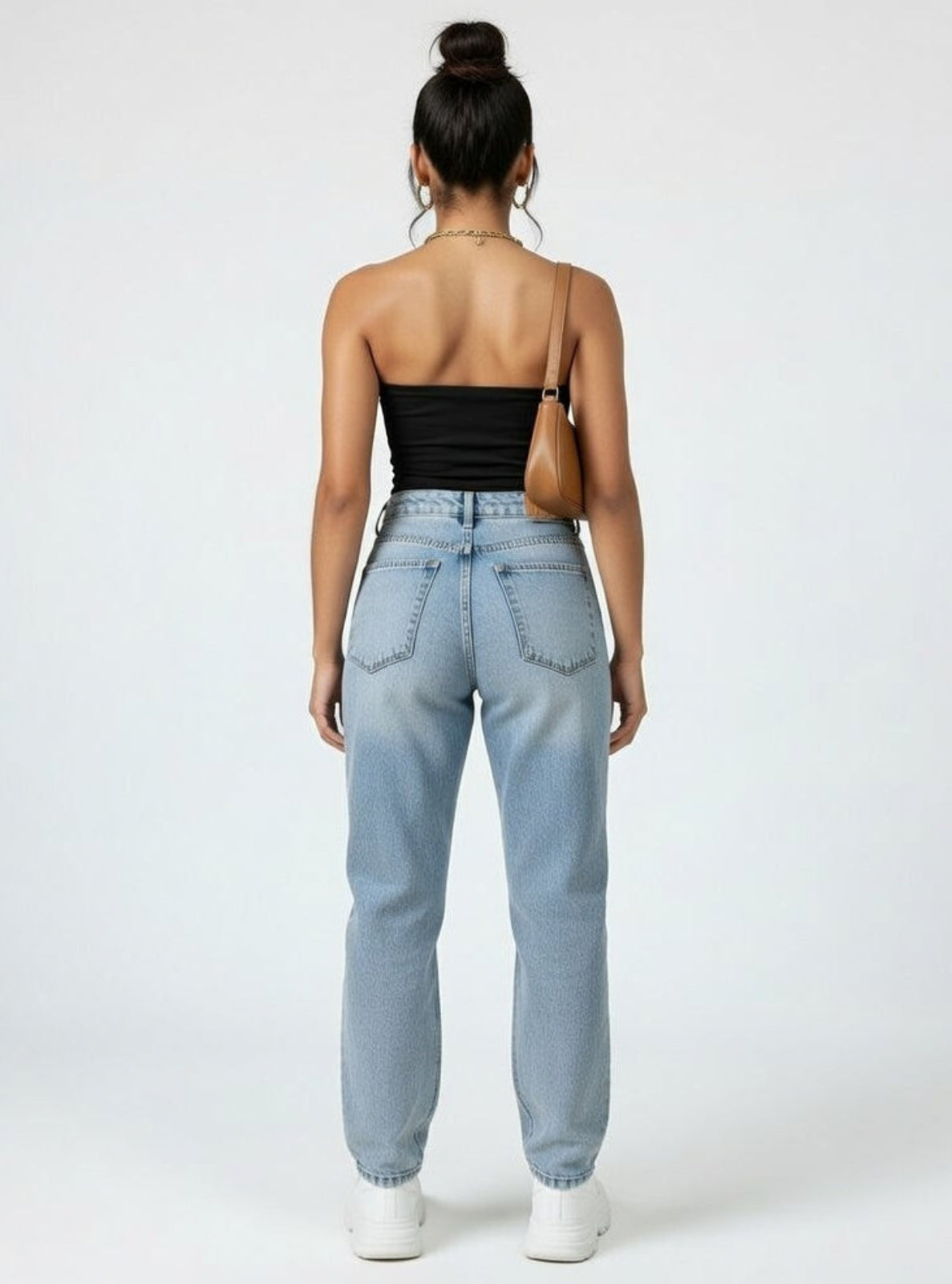 Person wearing light blue jeans and a black top on a white background