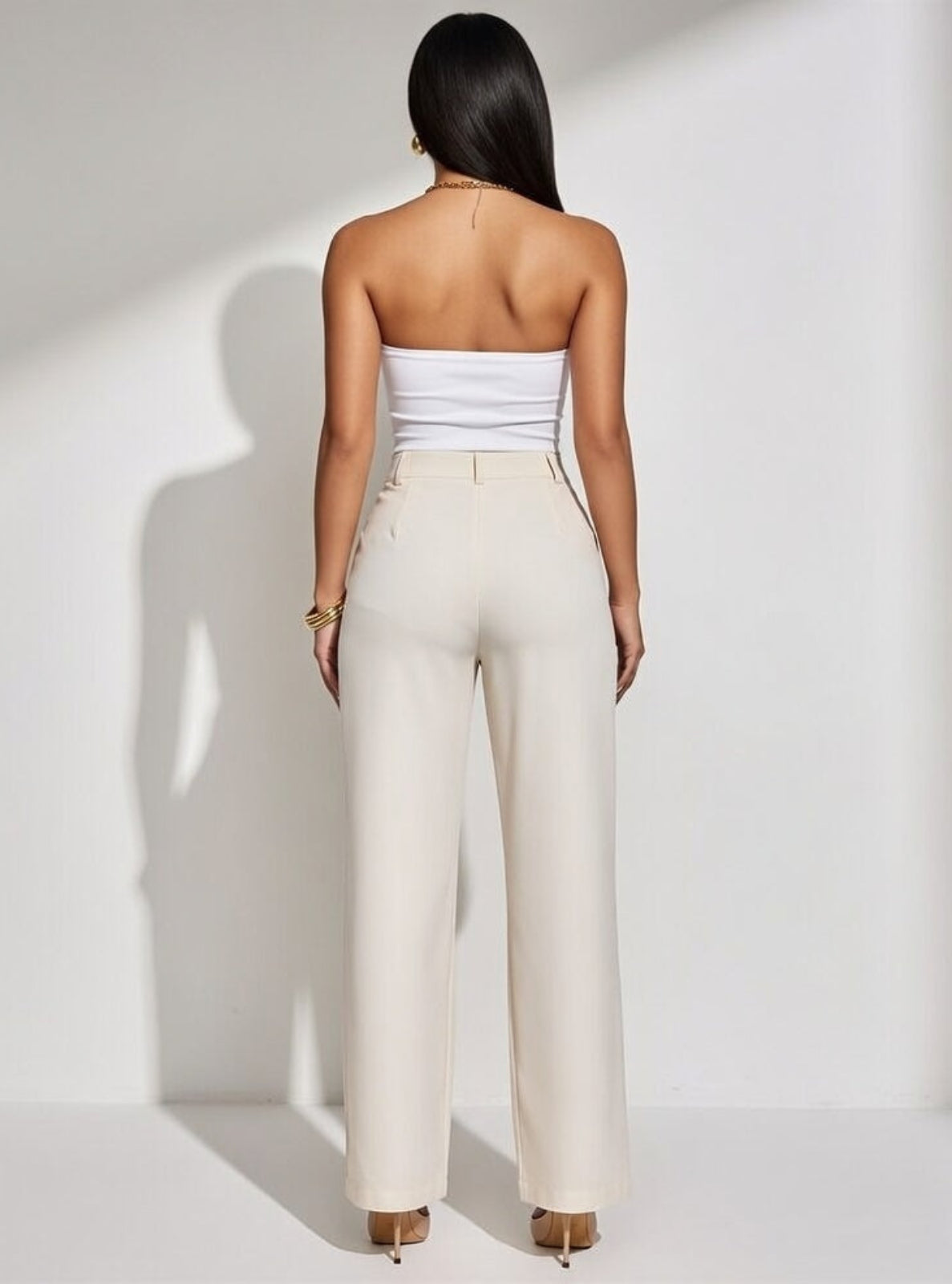 Woman wearing a white strapless top and beige pants against a white background