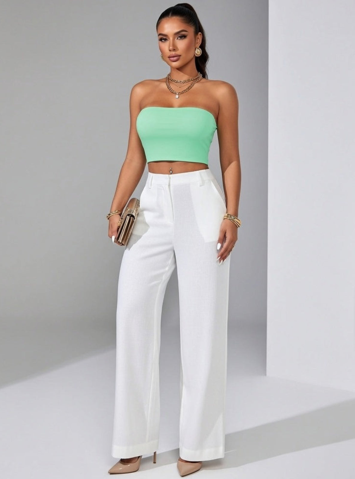 Woman wearing a green top and white pants against a gray background