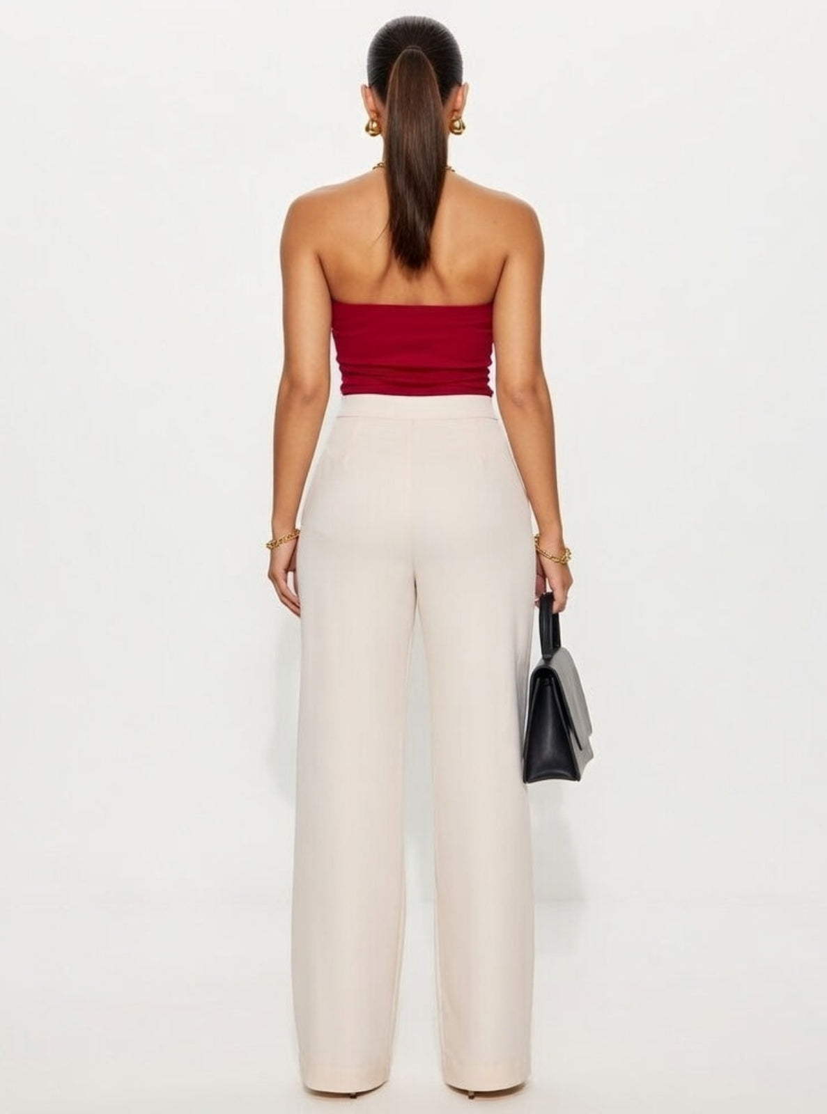 Woman wearing a red strapless top and beige pants on a white background