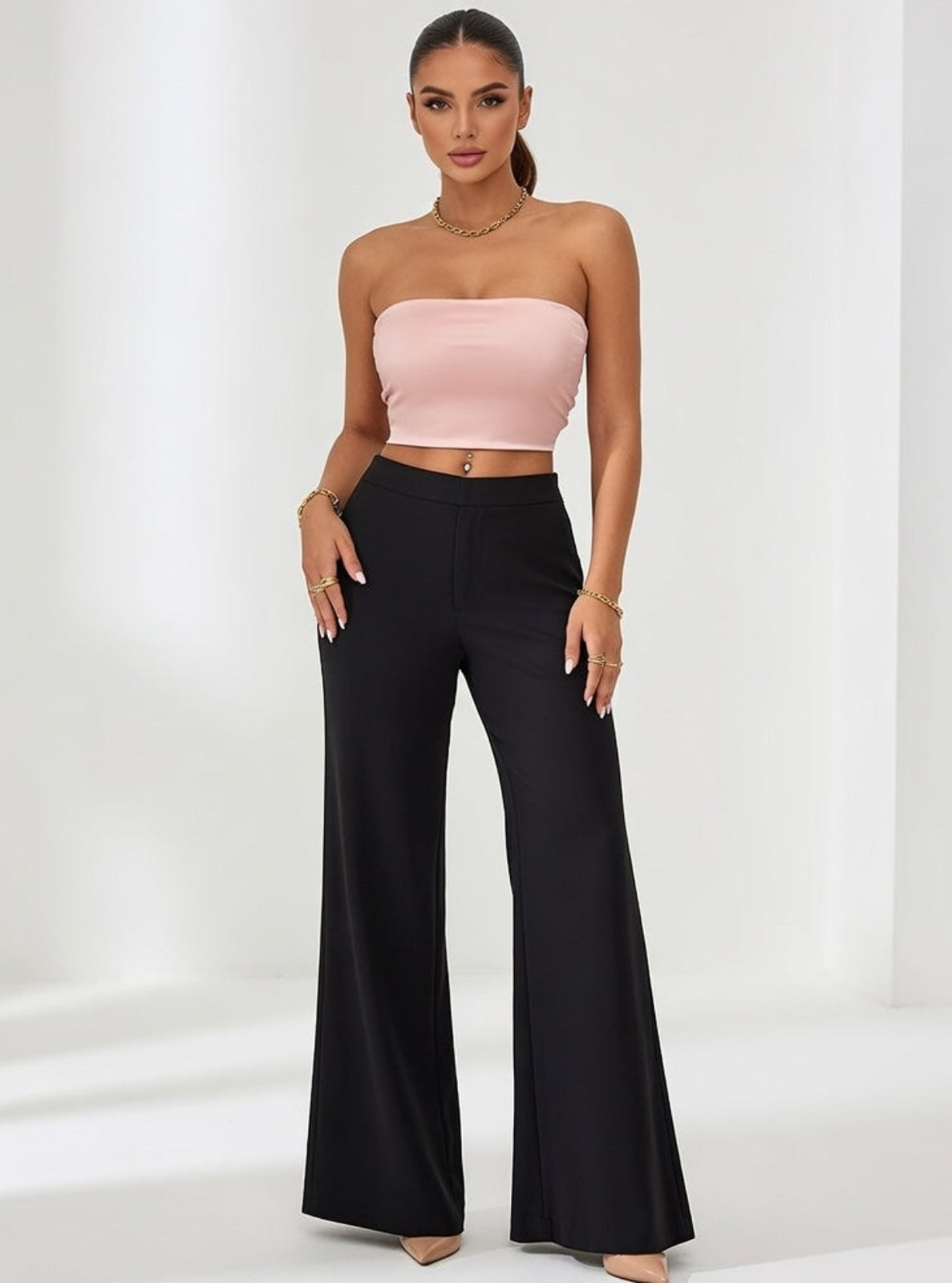 Woman wearing a pink strapless top and black wide-leg pants on a white background