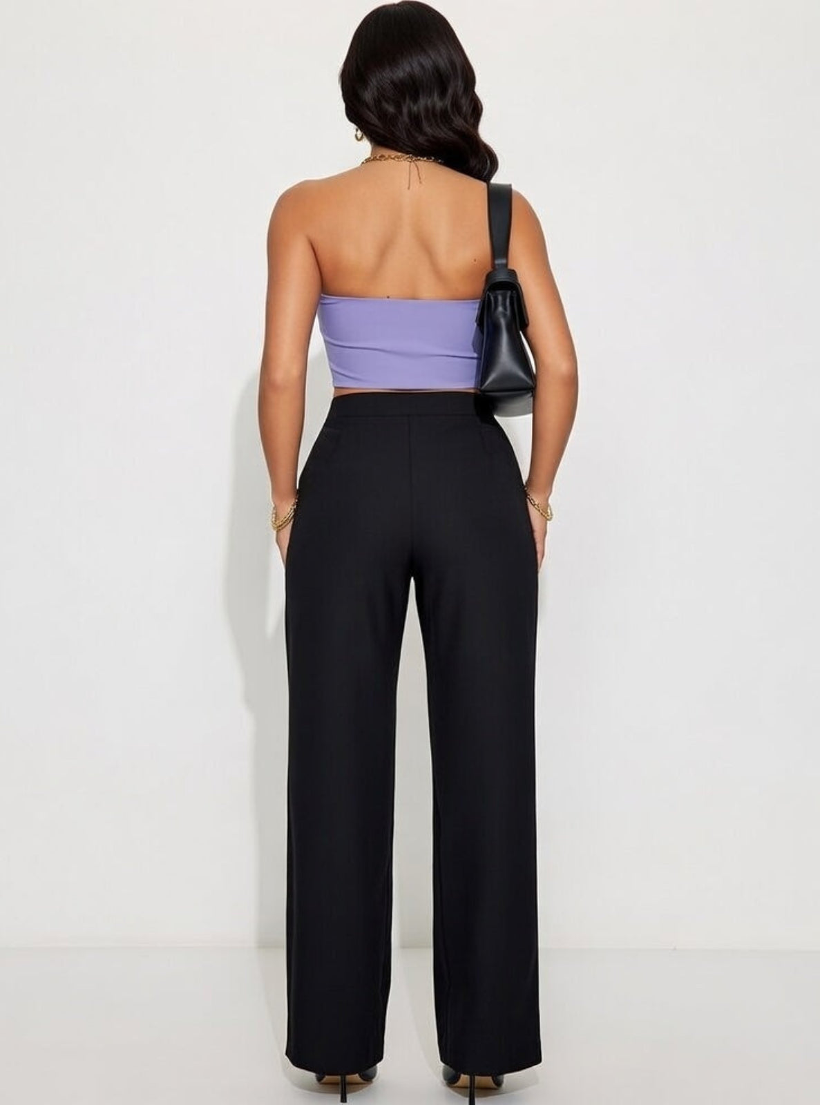 Woman wearing a purple top and black pants against a white background